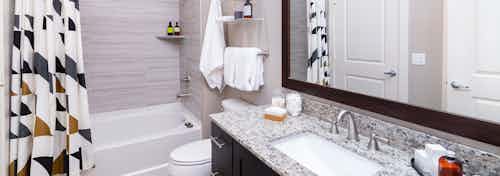 Interior of AMLI Littleton Village apartment bathroom with granite countertops, soaking tub and tile surround and soap holder