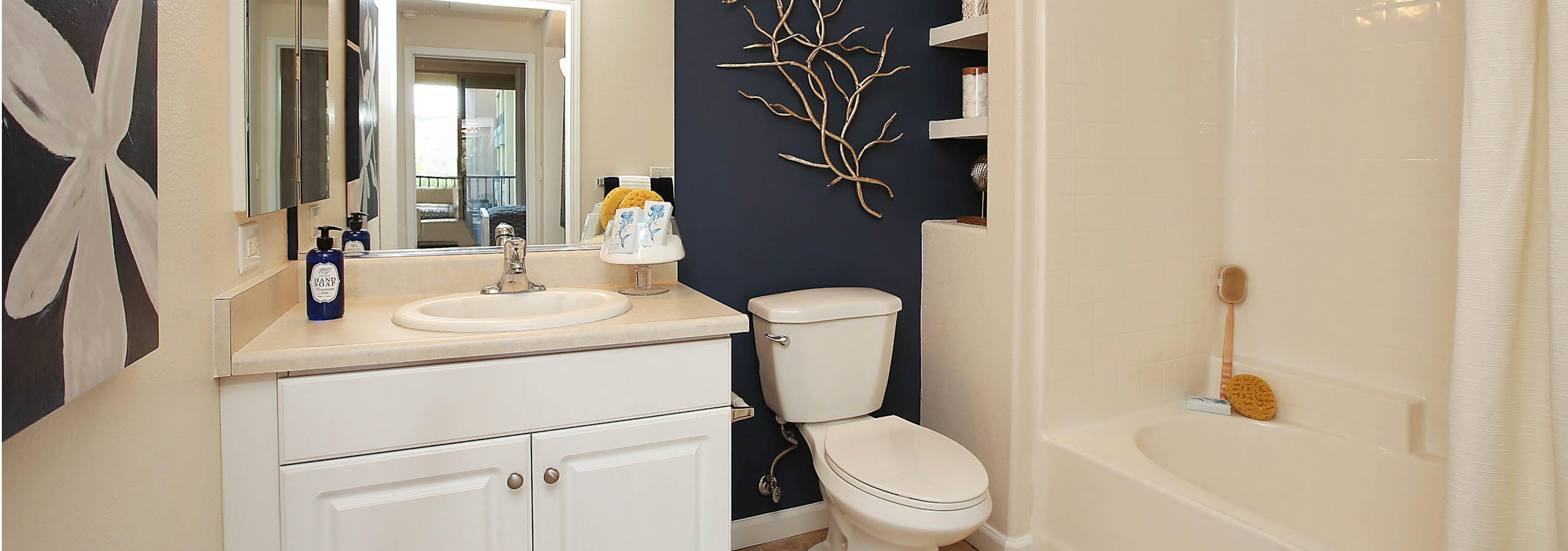 Interior view of AMLI Warner Center apartment bathroom with oversized garden tub, blue accent wall and wall art of flower