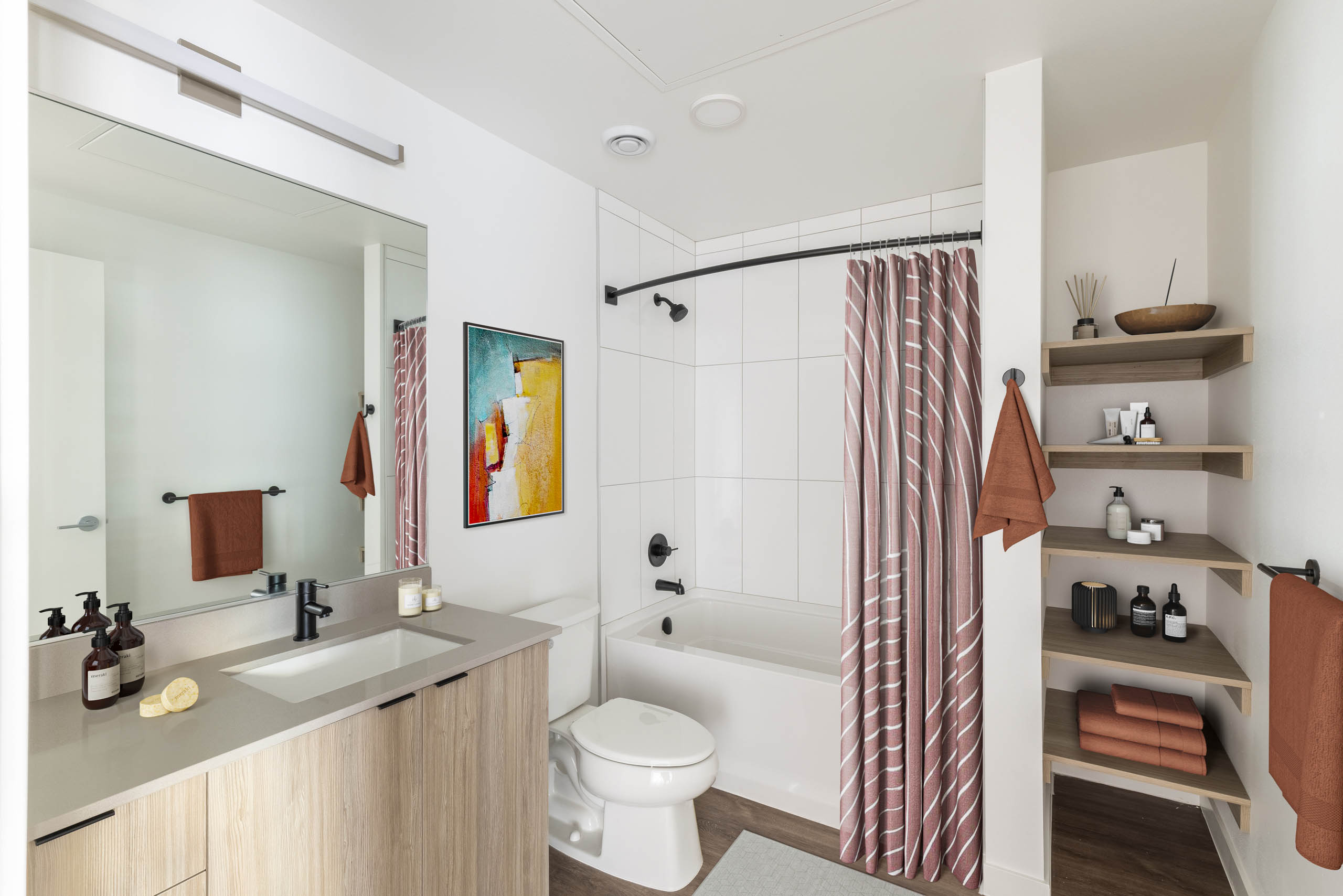 Bathroom at AMLI Redmond Way apartments with white tiles and a large bath tub surrounded by a shower curtain