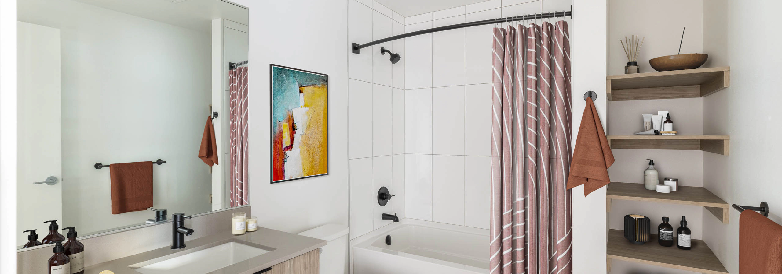 Bathroom at AMLI Redmond Way apartments with white tiles and a large bath tub surrounded by a shower curtain