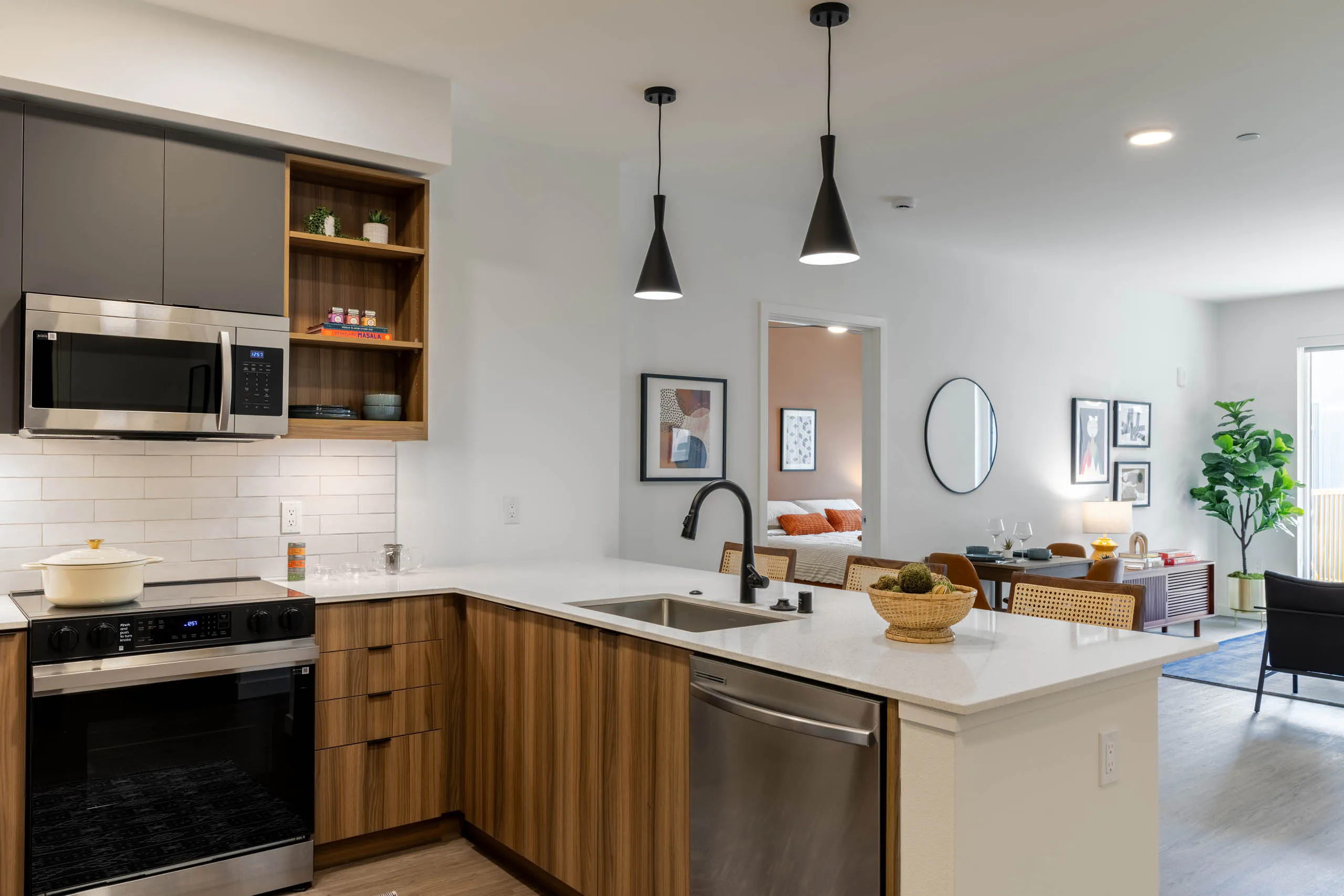 Kitchen area with stainless-steel appliances, wooden cabinetry and plank flooring connected to the living area.