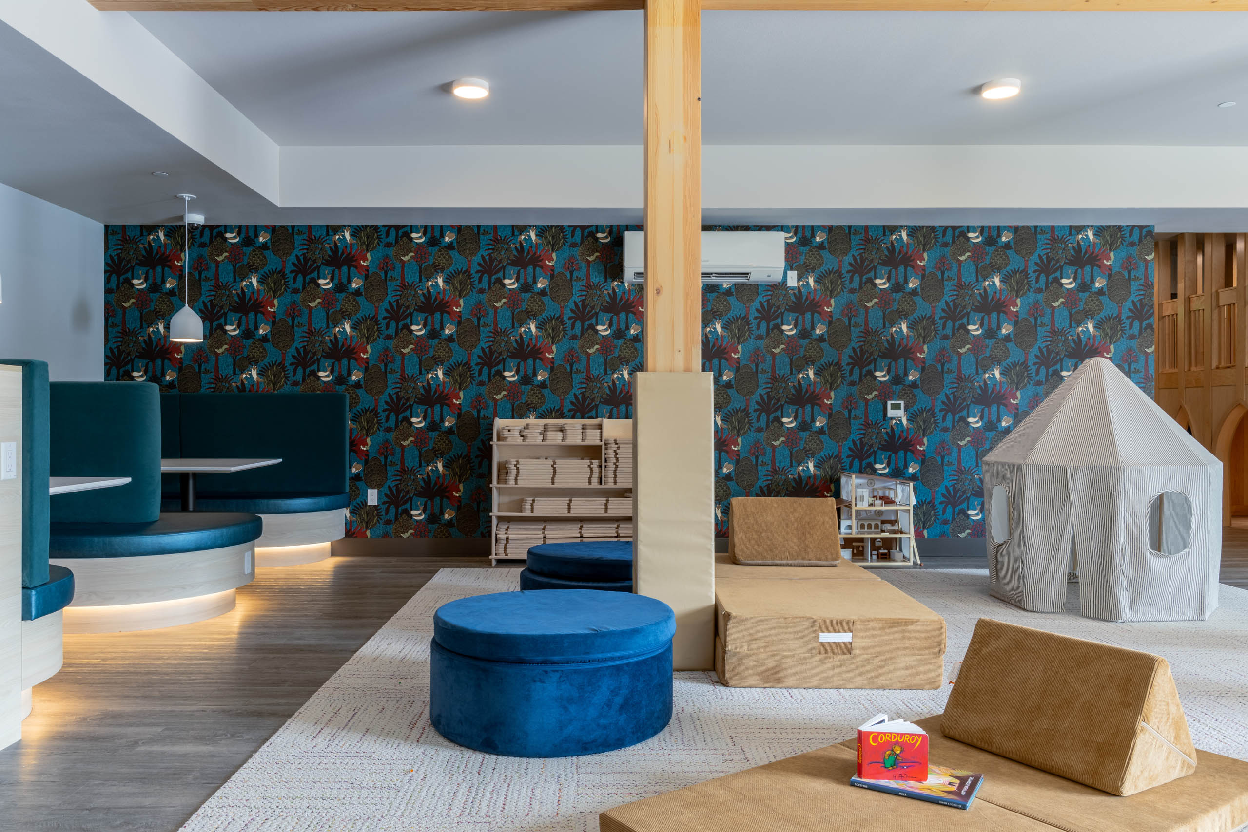 Interactive soft play area with blue seating for socializing and colorful patterned walls.