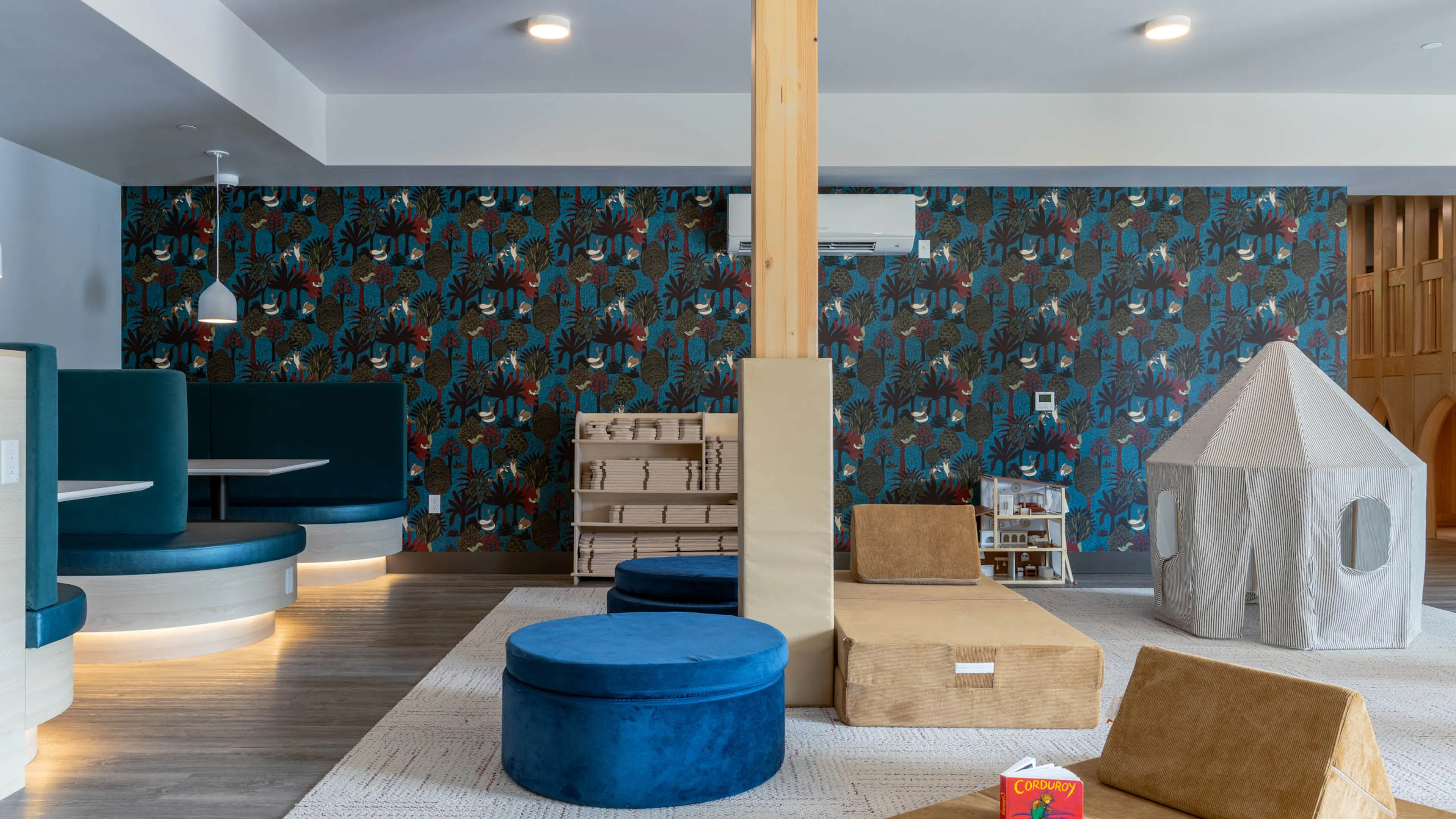 Interactive soft play area with blue seating for socializing and colorful patterned walls.