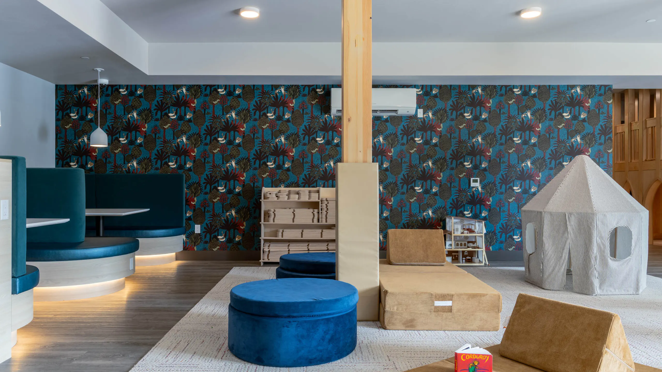 Interactive soft play area with blue seating for socializing and colorful patterned walls.