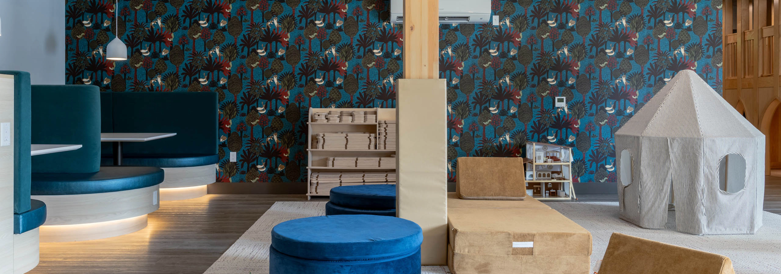 Interactive soft play area with blue seating for socializing and colorful patterned walls.