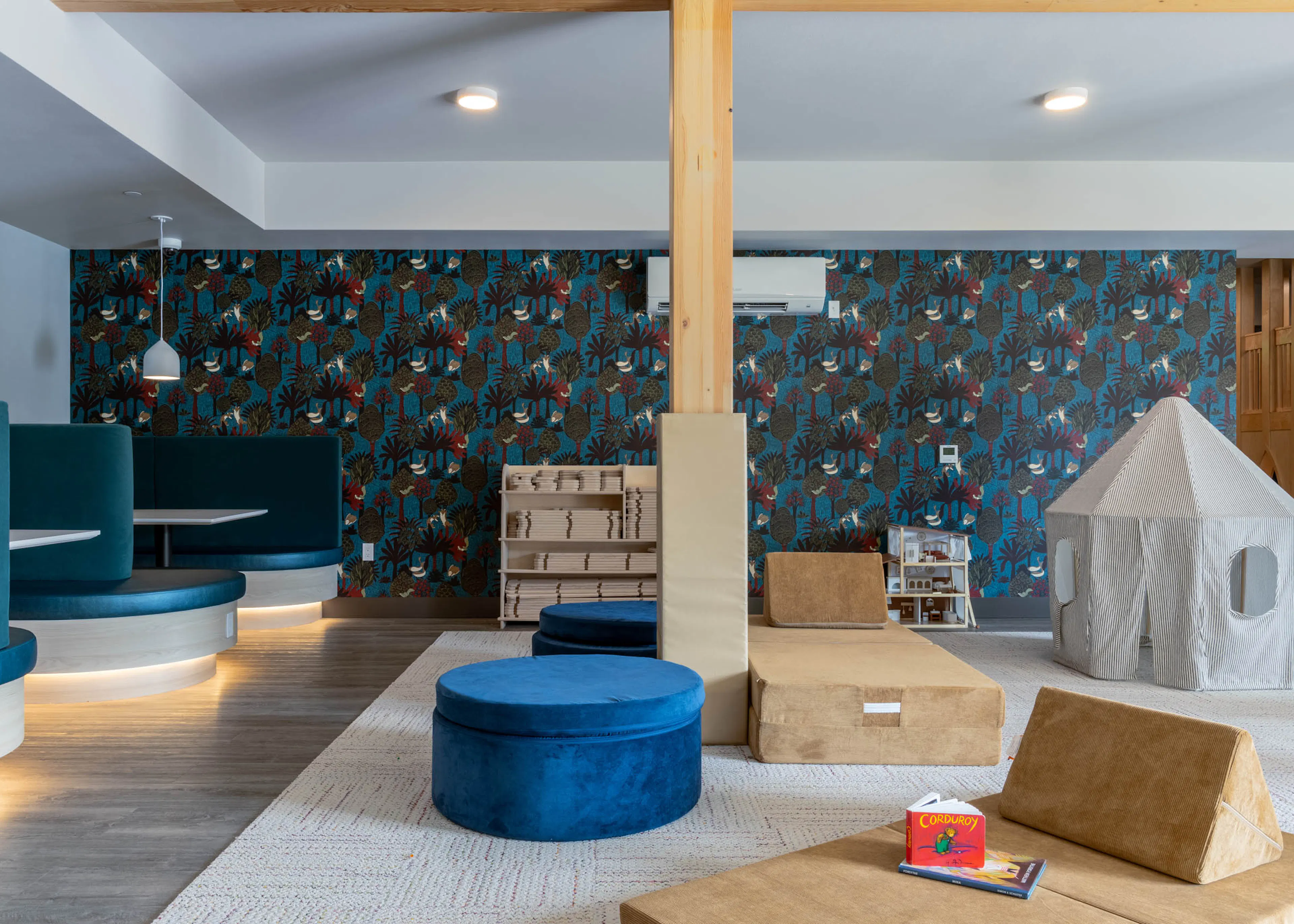 Interactive soft play area with blue seating for socializing and colorful patterned walls.