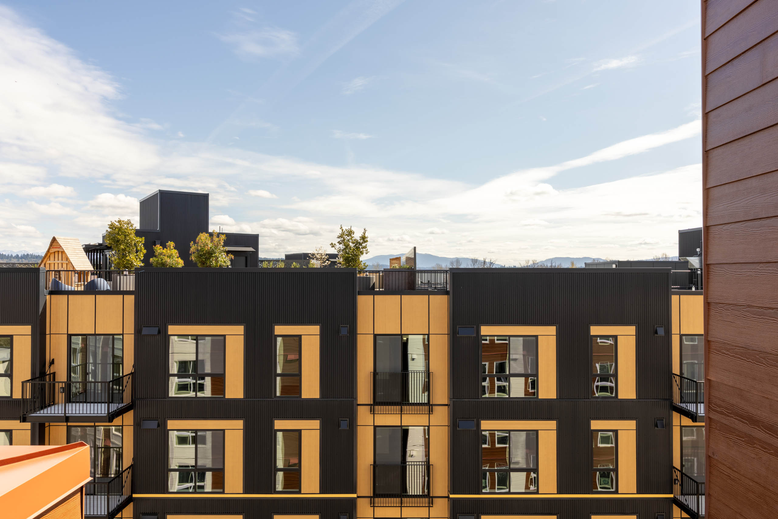 AMLI Redmond Way brown and black exterior with balconies and a rooftop terrace, with views of the area behind the building.