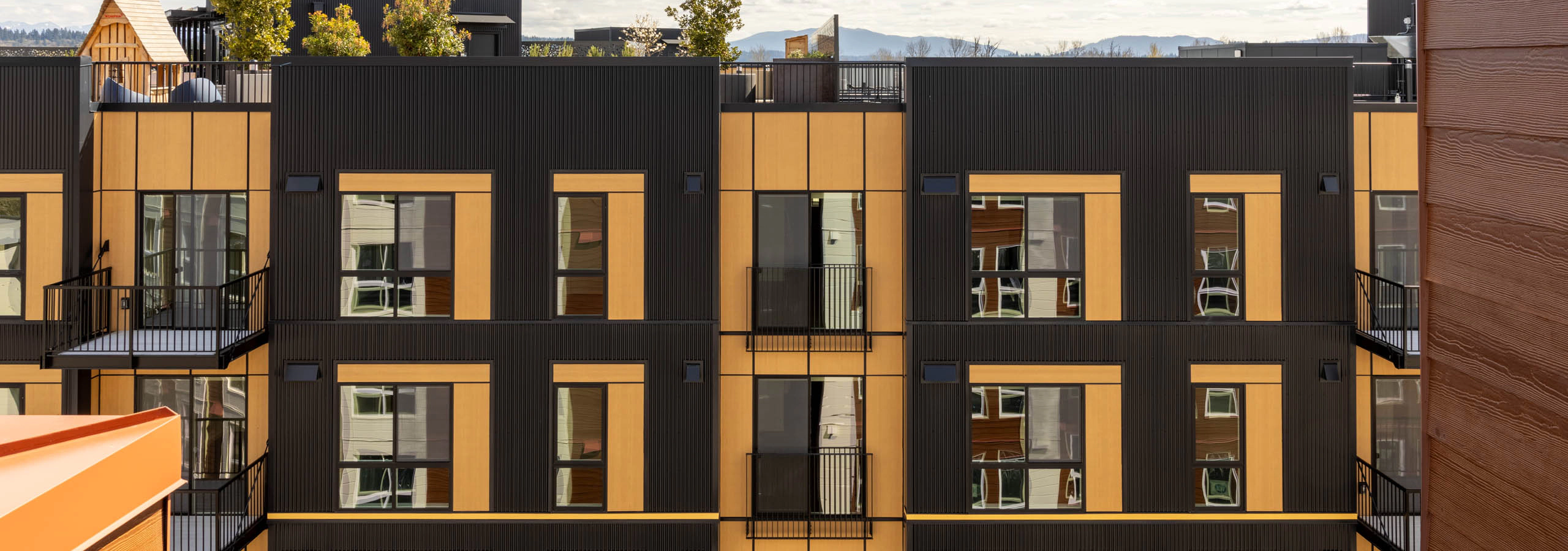 AMLI Redmond Way brown and black exterior with balconies and a rooftop terrace, with views of the area behind the building.