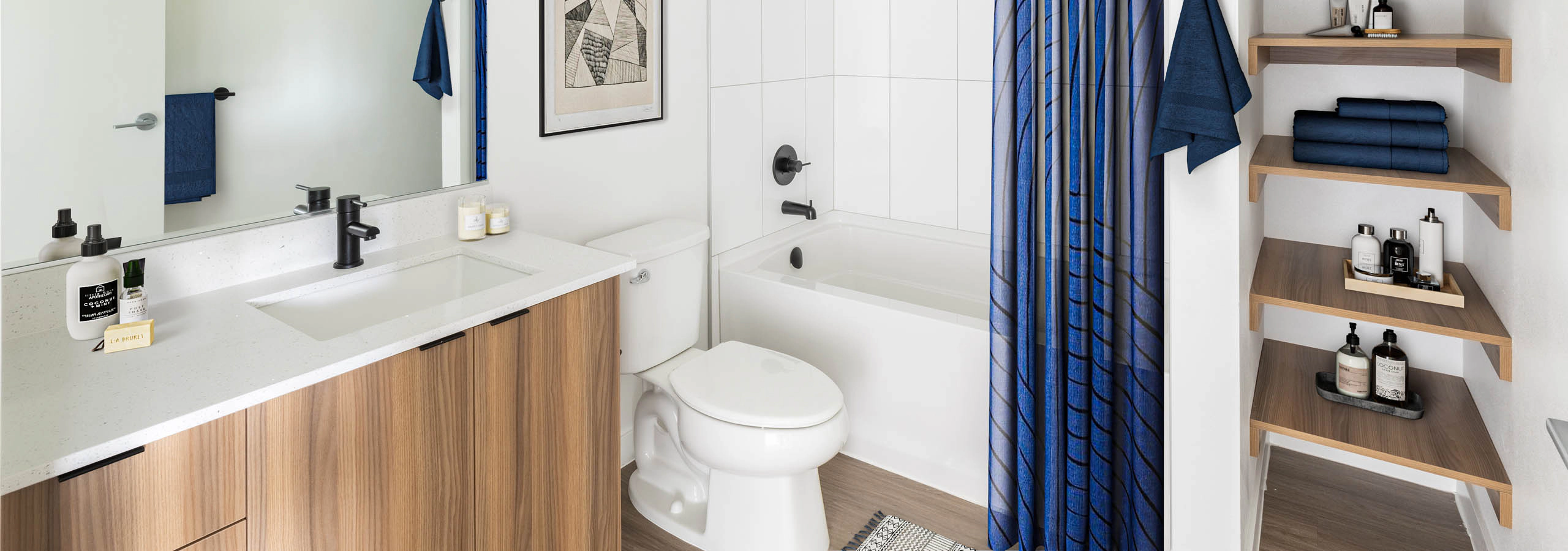 Interior view of AMLI Redmond Way apartment bathroom with soaking tub, open wood shelving, and large mirror with modern vanity.