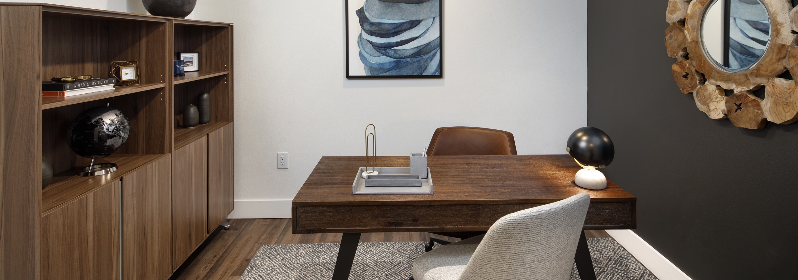 Interior of AMLI Marina Del Rey apartment office space with area rug, wood desk and two chairs and wall unit with storage