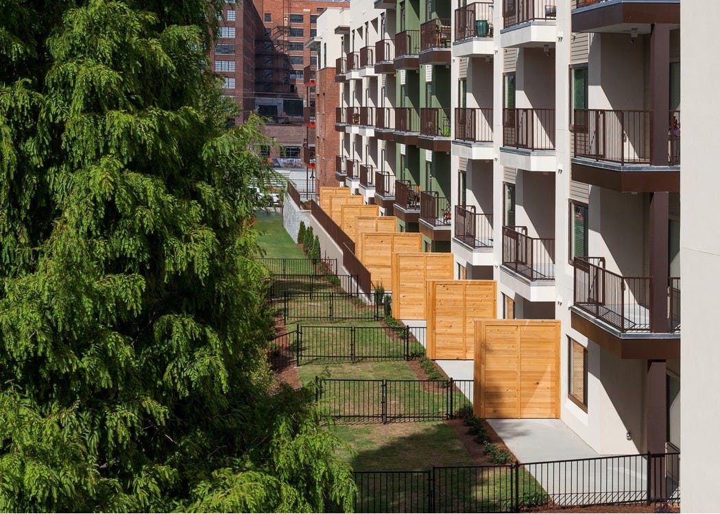 Exterior view of AMLI Ponce Park bottom floor apartments containing small private yards with iron fences separating them