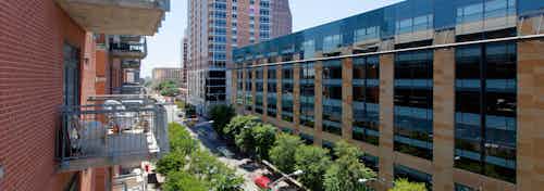View from another balcony at AMLI Downtown facing a long city building with vibrant shrubbery and trees and a blue sky