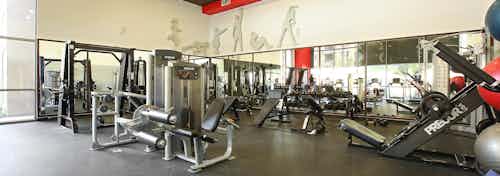 Interior of fitness center with workout equipment, free weights and surrounding mirrors at AMLI Warner Center apartments