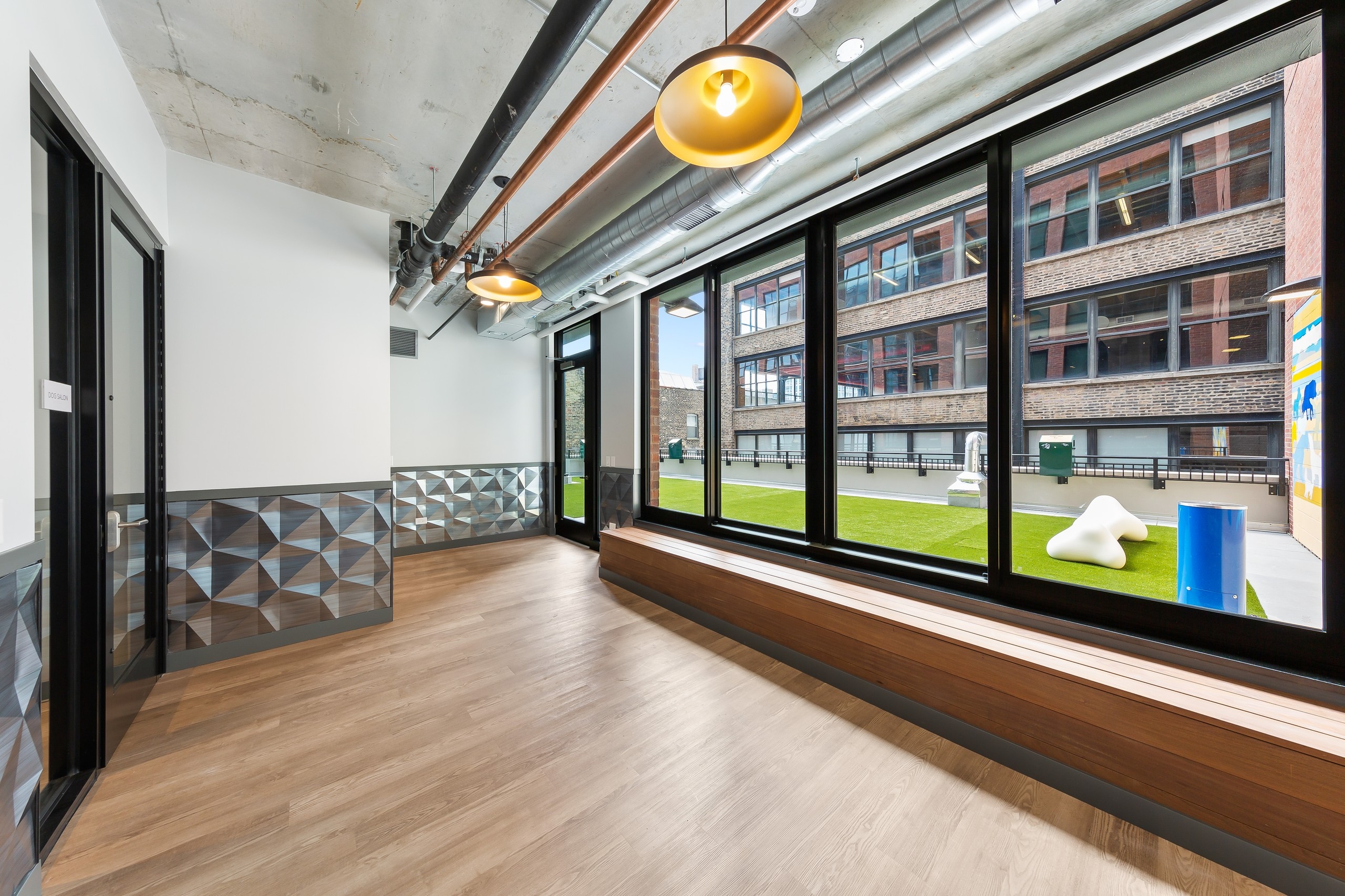 Pet lounge at AMLI 808 with open space and loft ceilings with view out of large windows revealing outdoor pet area 