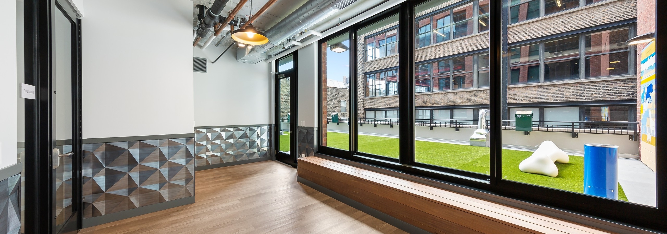 Pet lounge at AMLI 808 with open space and loft ceilings with view out of large windows revealing outdoor pet area