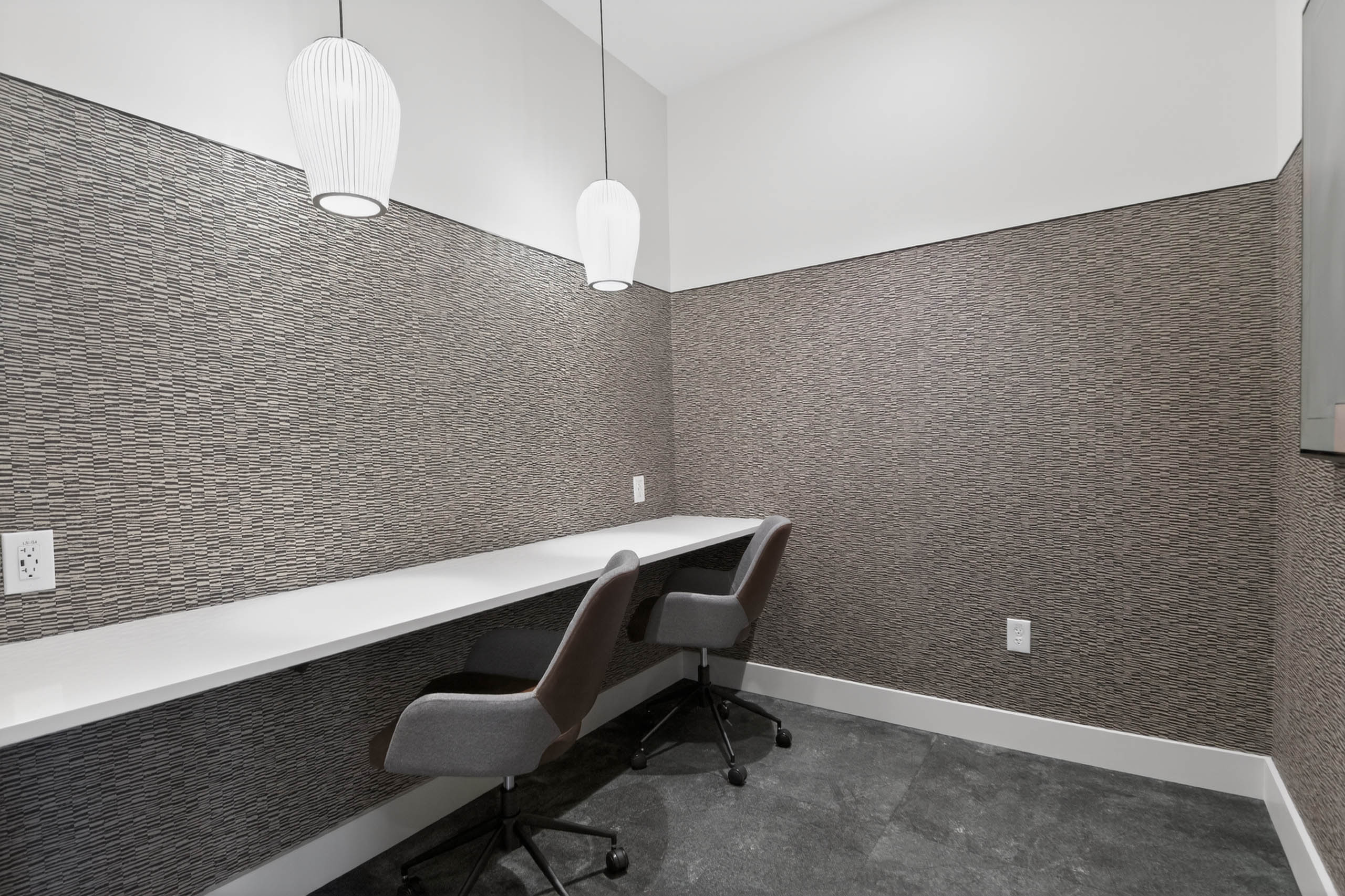 Private working office at AMLI Golden Triangle apartments with long counter task chairs textured walls and pendant lighting