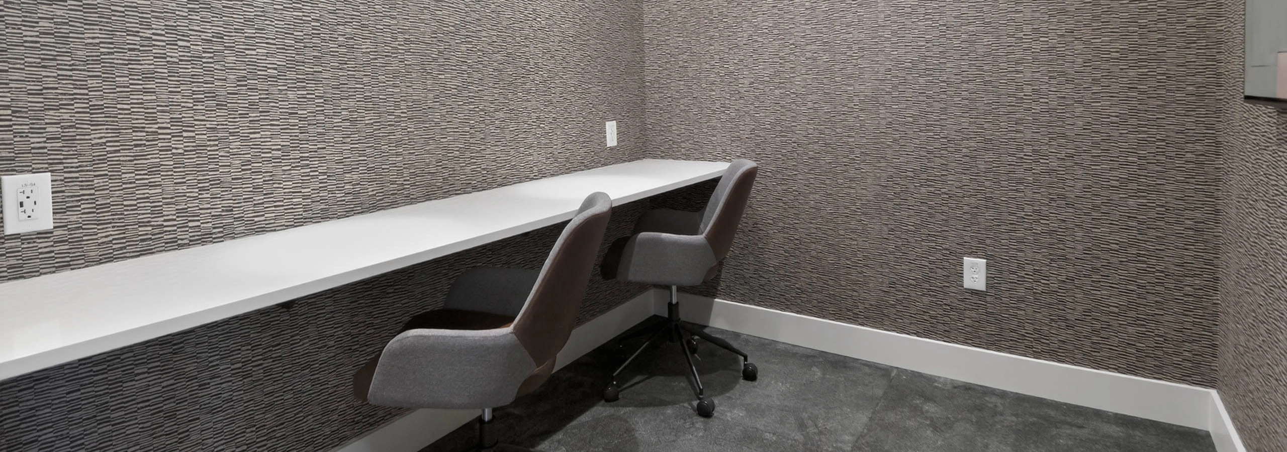 Private working office at AMLI Golden Triangle apartments with long counter task chairs textured walls and pendant lighting