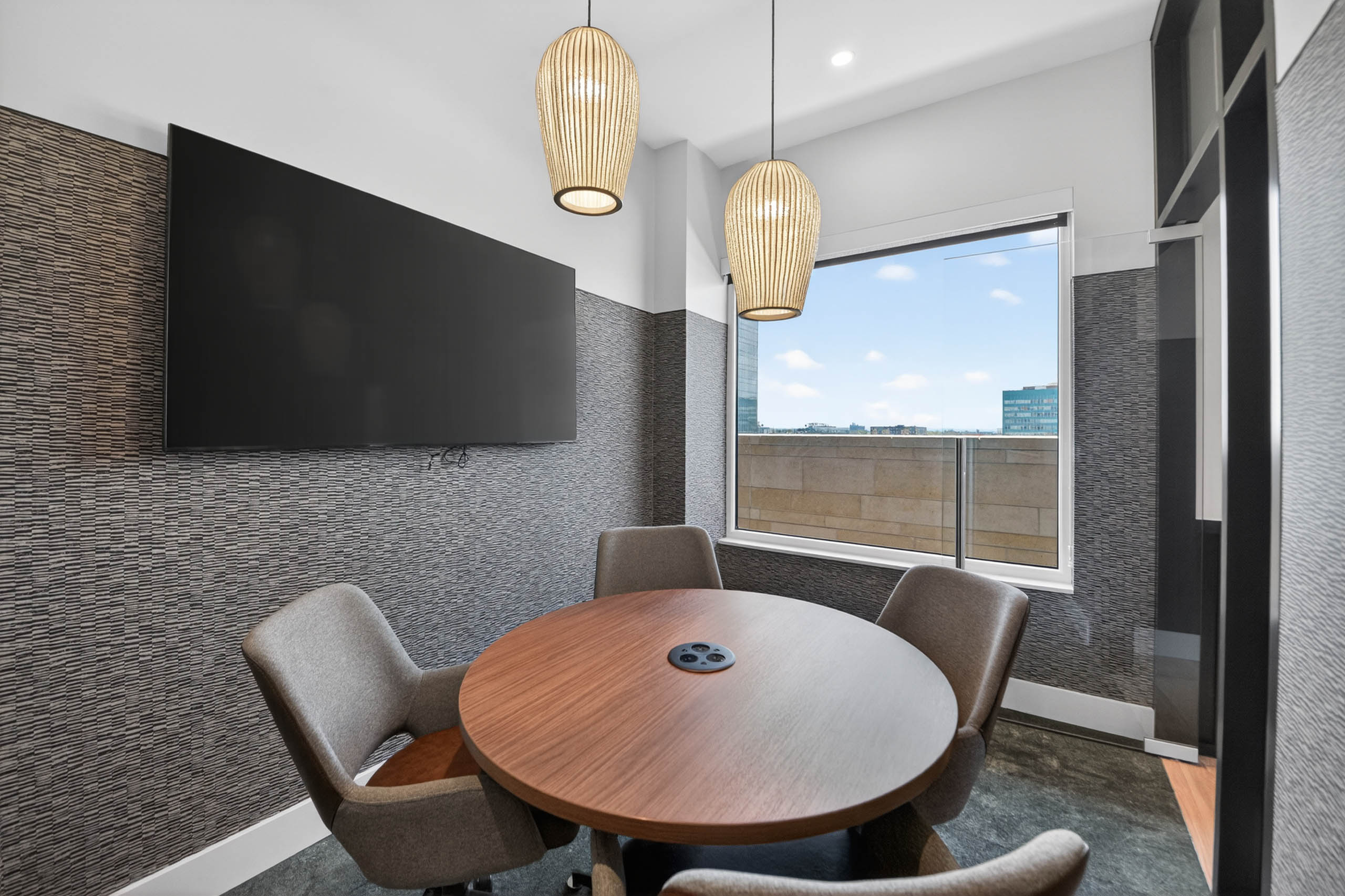 Private conference room at AMLI Golden Triangle apartments with round table wall mounted screen and window views