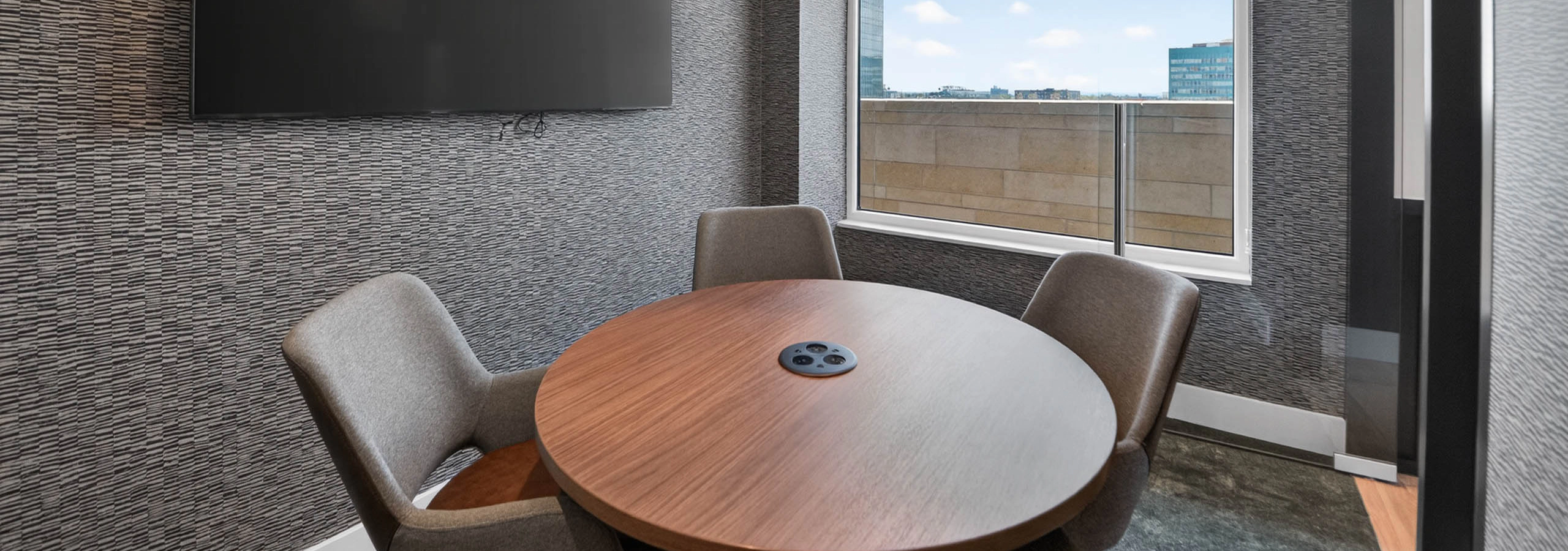 Private conference room at AMLI Golden Triangle apartments with round table wall mounted screen and window views