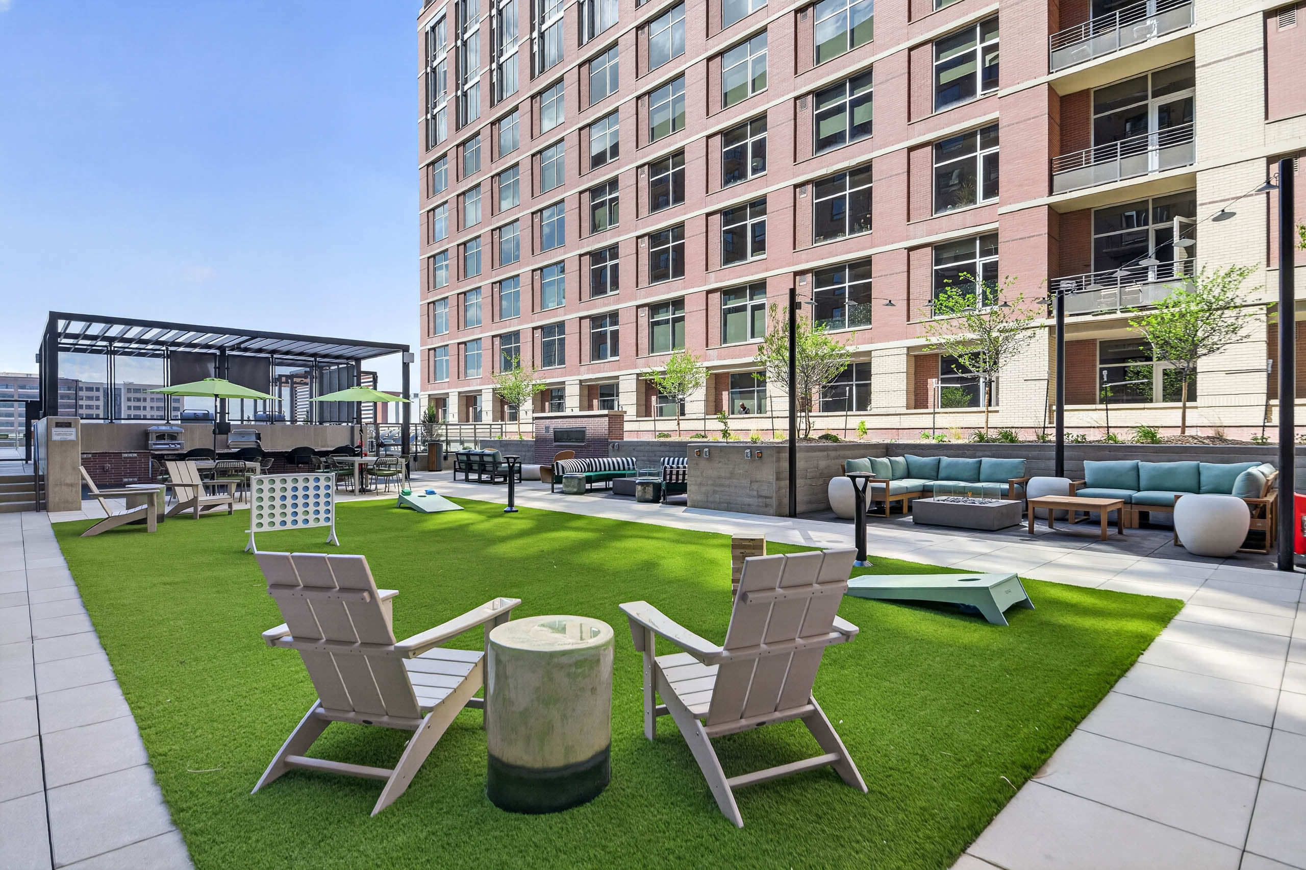Outdoor lounge at AMLI Golden Triangle apartments with sectional seating fire pit string lights and landscaped courtyard