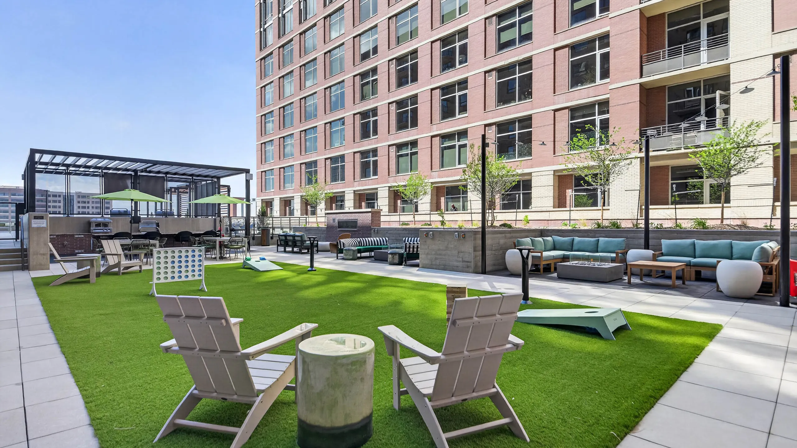 Outdoor lounge at AMLI Golden Triangle apartments with sectional seating fire pit string lights and landscaped courtyard
