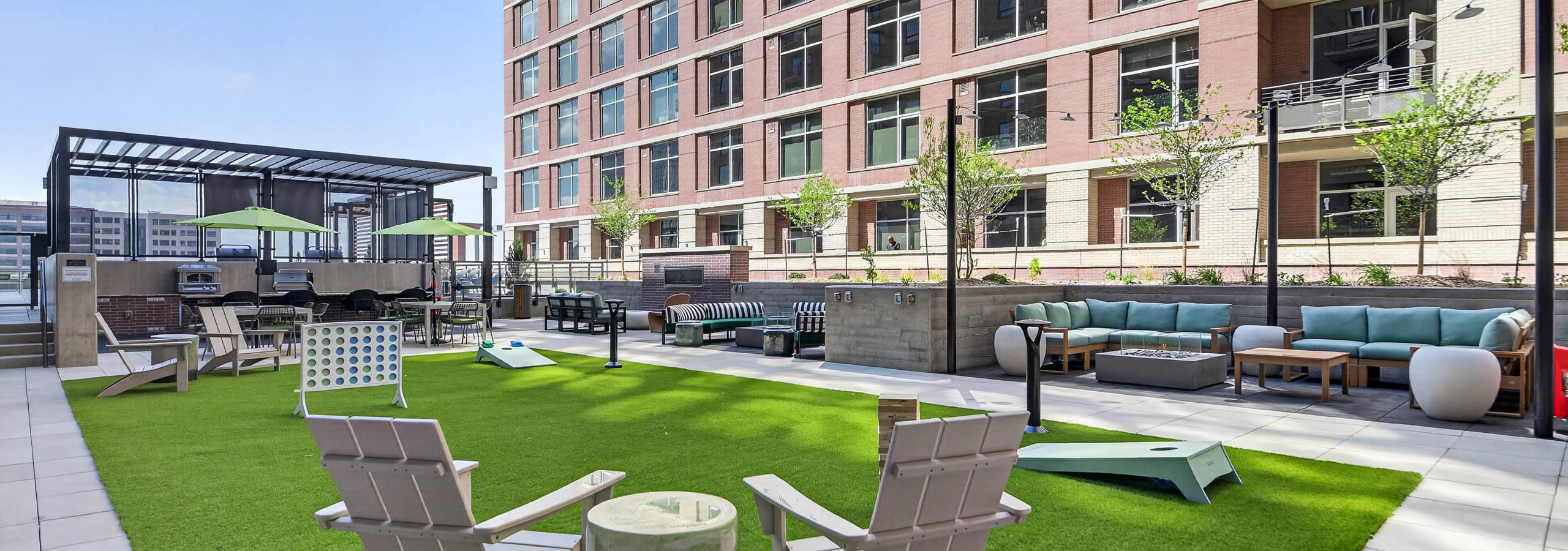 Outdoor lounge at AMLI Golden Triangle apartments with sectional seating fire pit string lights and landscaped courtyard