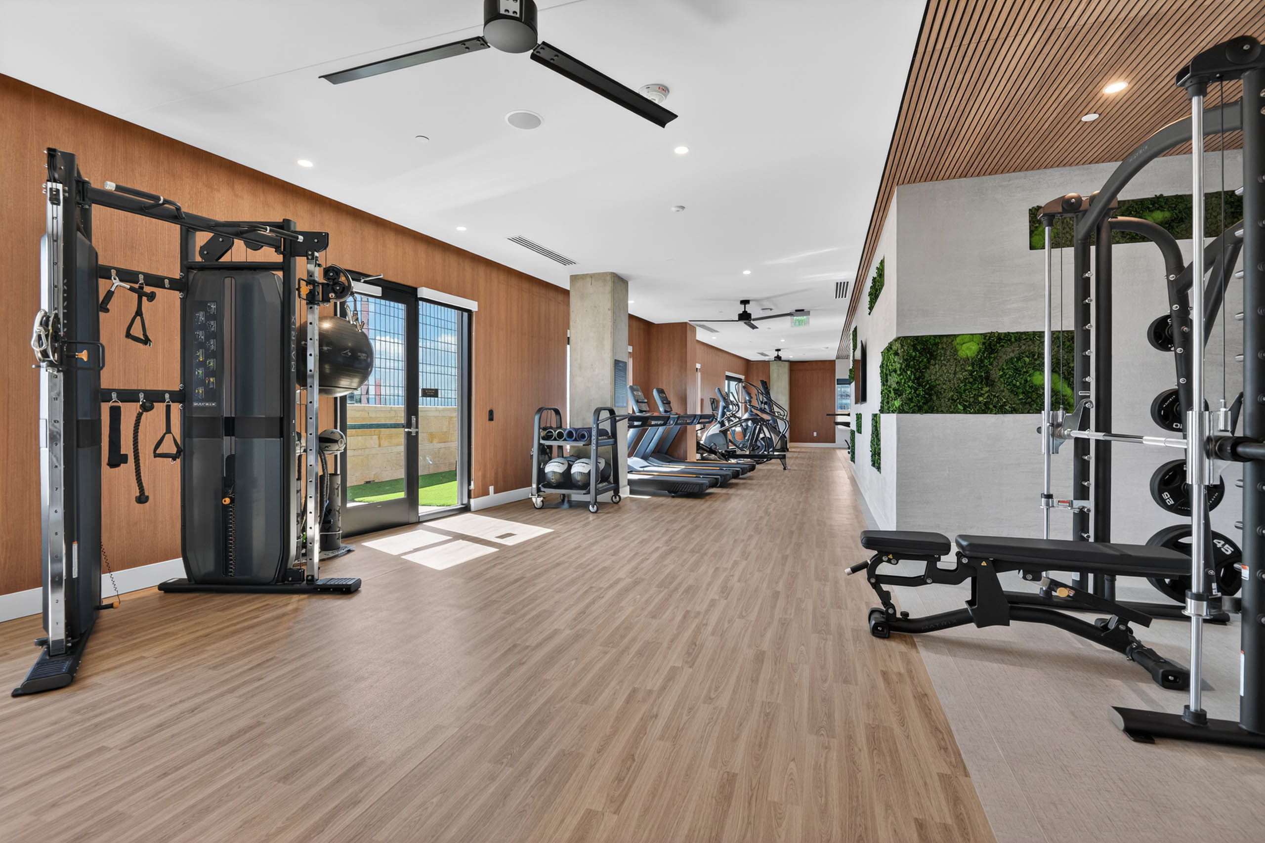 Fitness center at AMLI Golden Triangle apartments with strength machines cardio equipment open floor plan and turf area
