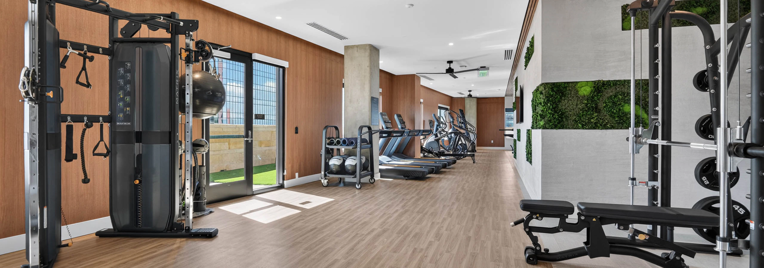 Fitness center at AMLI Golden Triangle apartments with strength machines cardio equipment open floor plan and turf area