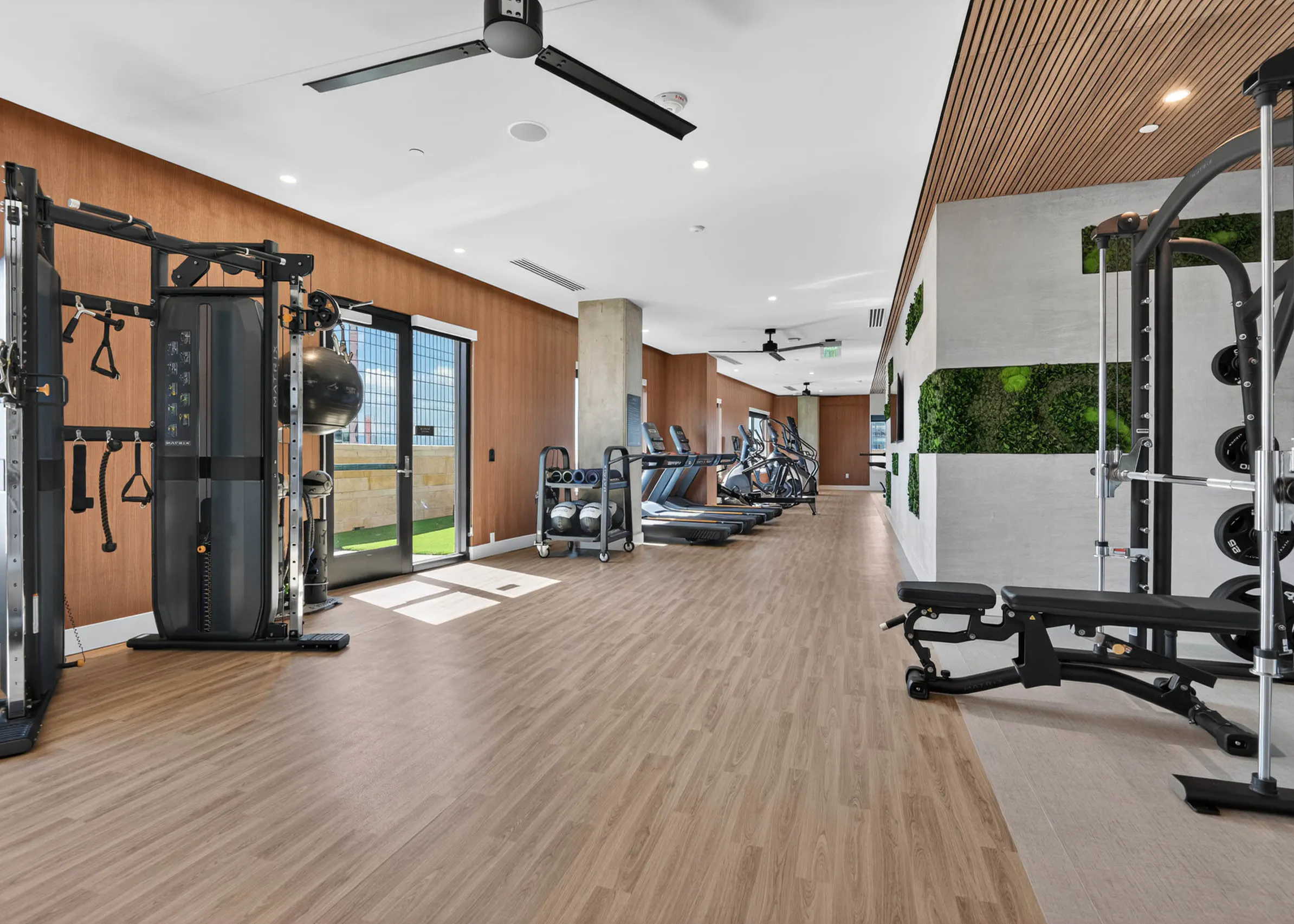 Fitness center at AMLI Golden Triangle apartments with strength machines cardio equipment open floor plan and turf area