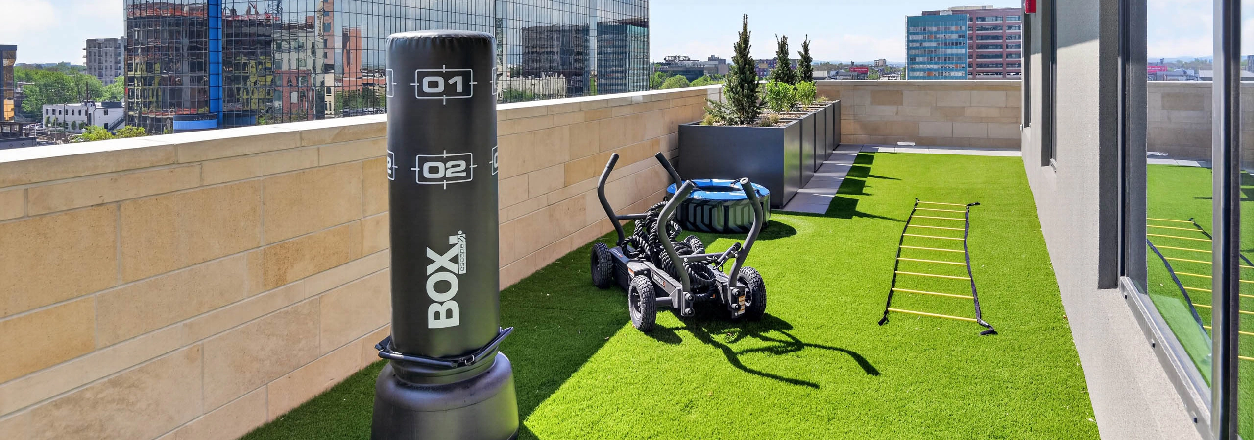 Outdoor fitness area at AMLI Golden Triangle apartments with turf surface punching bag training equipment and city views
