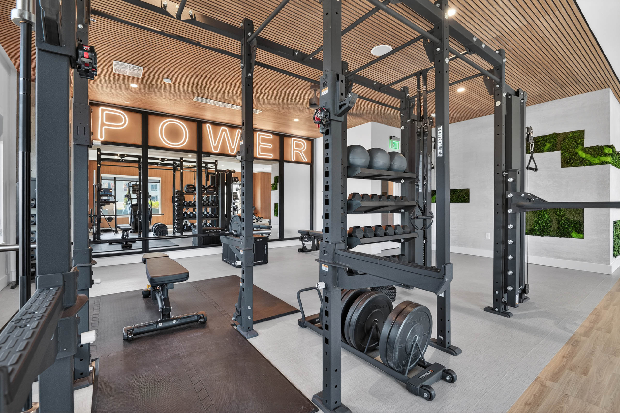 Modern gym at AMLI Golden Triangle apartments with power racks free weights training zone and illuminated signage
