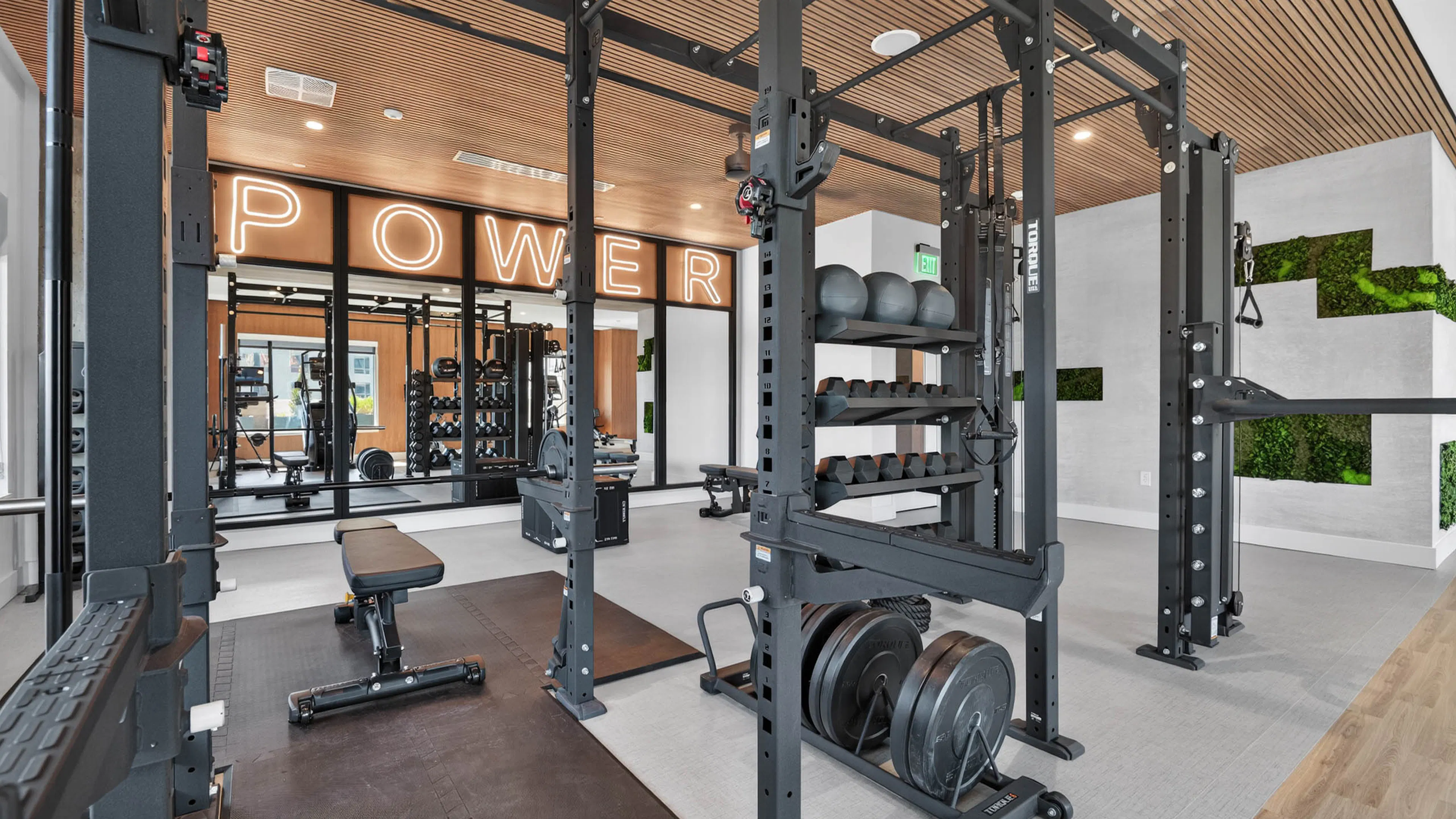 Modern gym at AMLI Golden Triangle apartments with power racks free weights training zone and illuminated signage