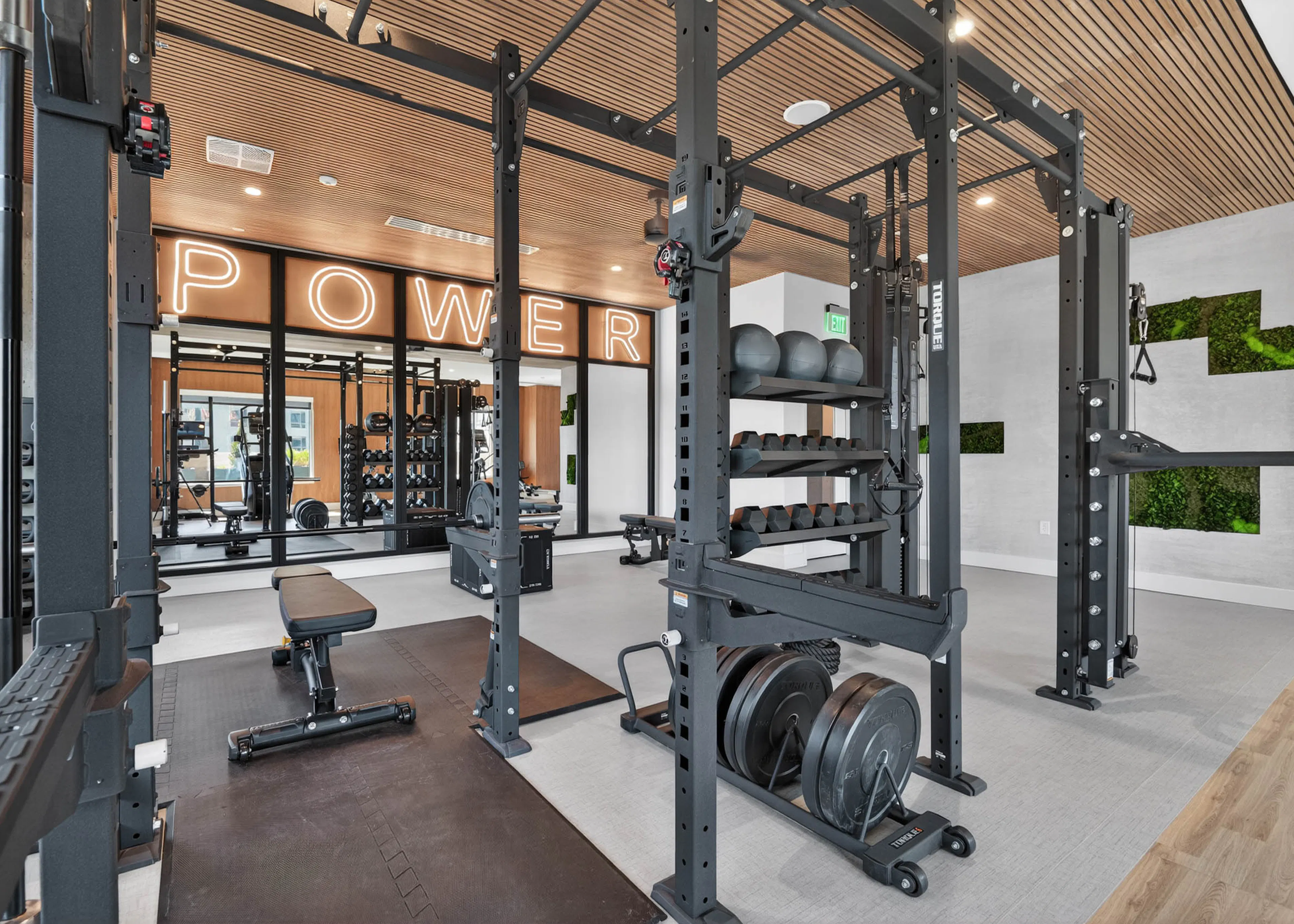 Modern gym at AMLI Golden Triangle apartments with power racks free weights training zone and illuminated signage