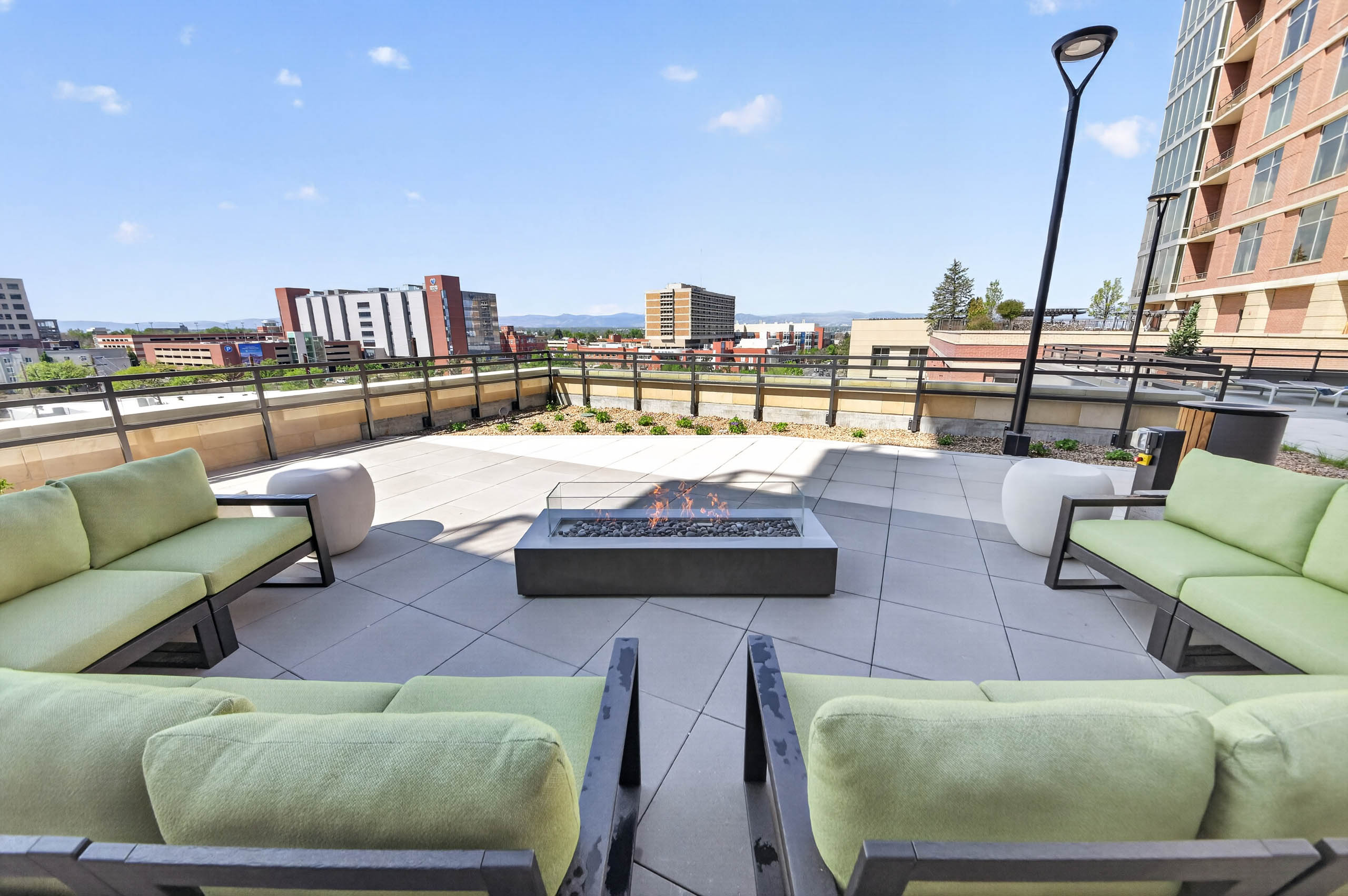 Outdoor fire pit at AMLI Golden Triangle apartments with cushioned seating modern lighting and distant mountain views