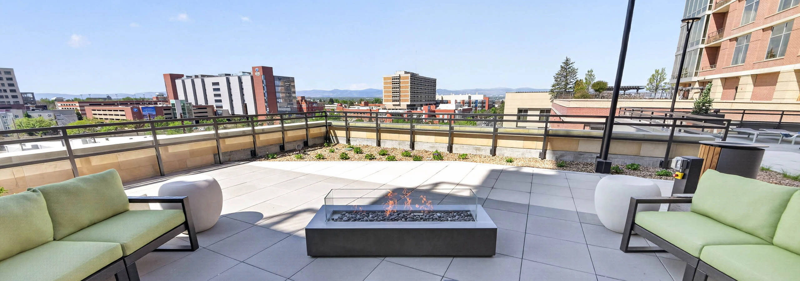 Outdoor fire pit at AMLI Golden Triangle apartments with cushioned seating modern lighting and distant mountain views