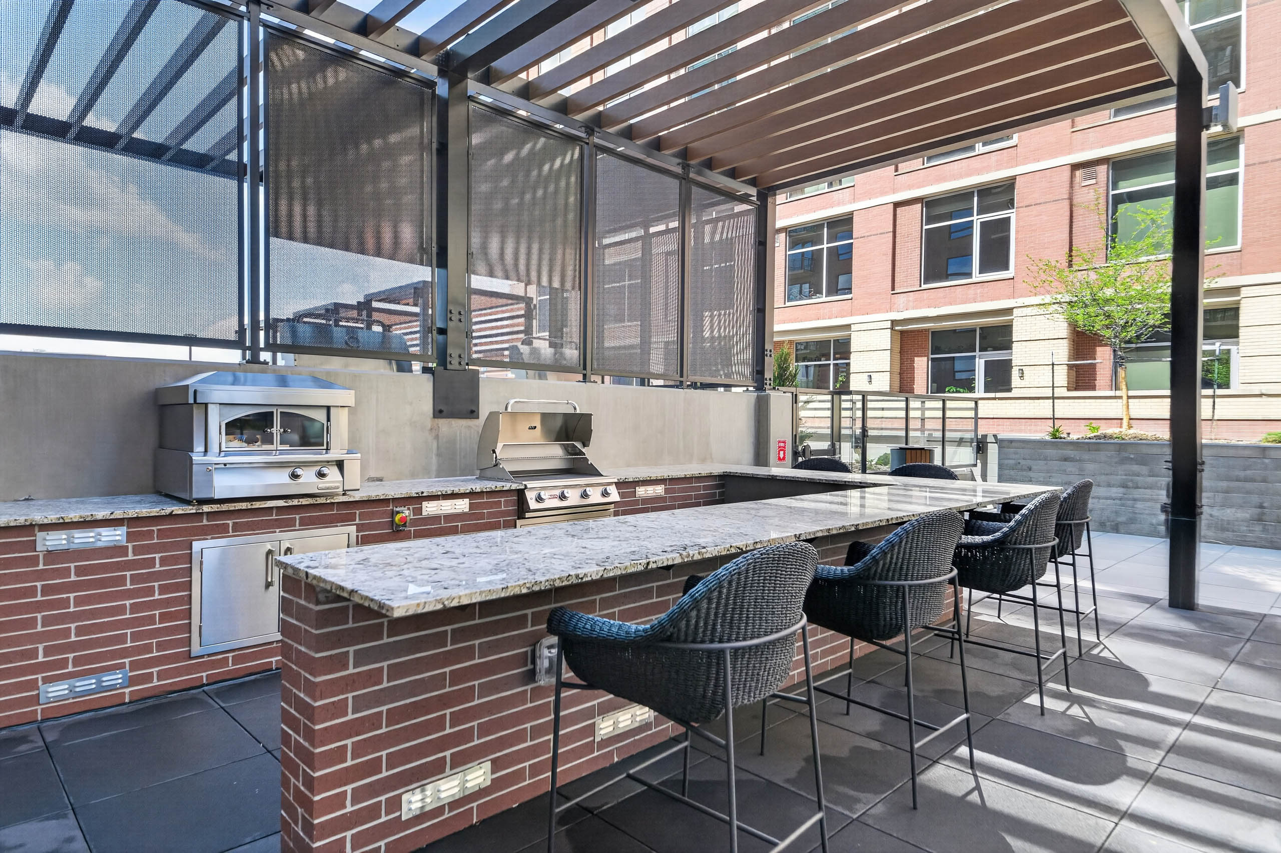 Outdoor terrace at AMLI Golden Triangle apartments with outdoor kitchen bar seating pizza oven and grill stations