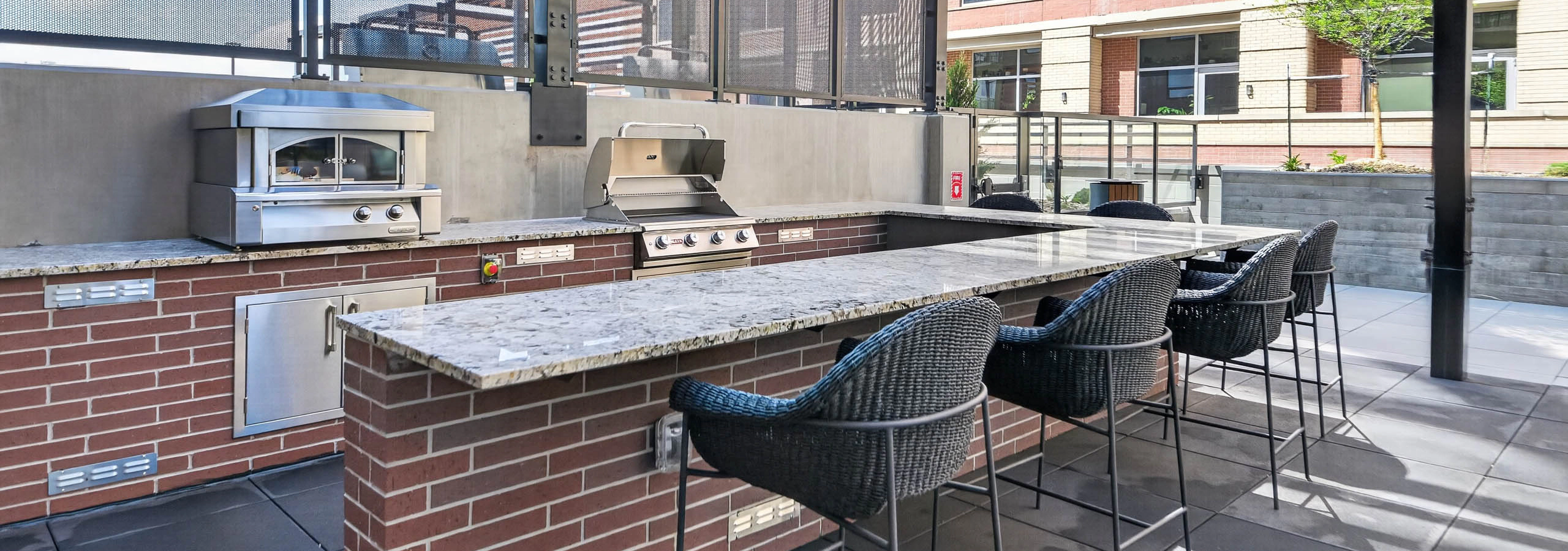 Outdoor terrace at AMLI Golden Triangle apartments with outdoor kitchen bar seating pizza oven and grill stations