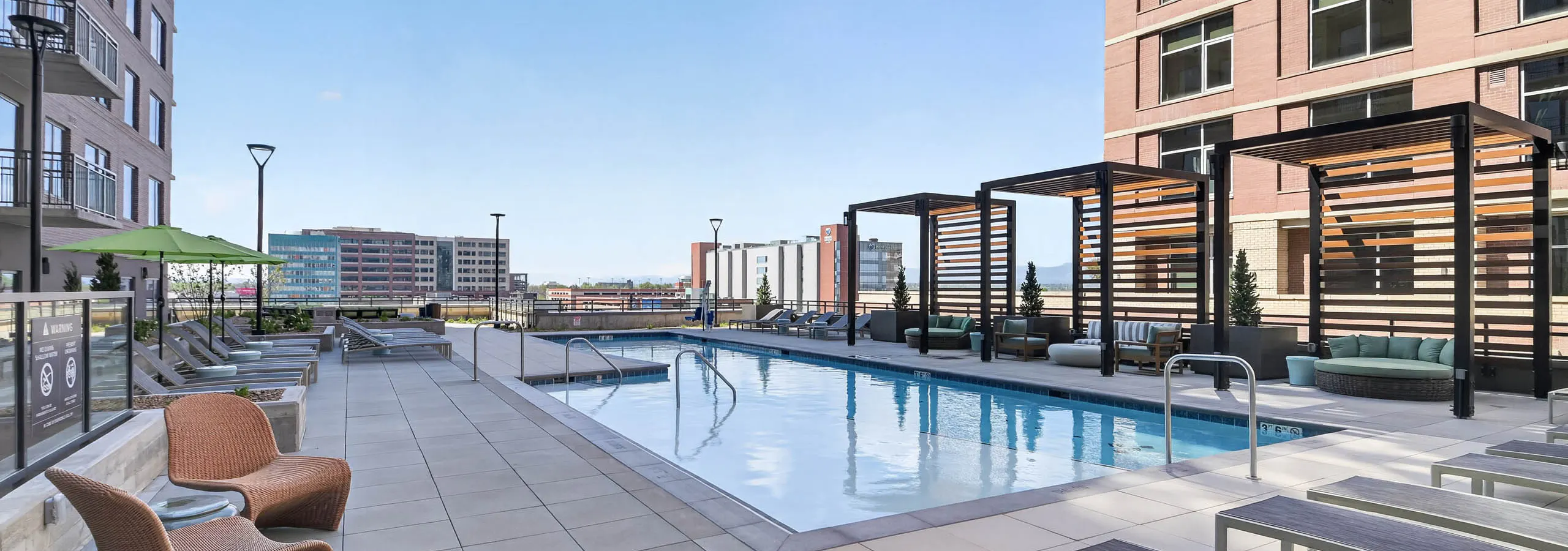 Resident pool at AMLI Golden Triangle apartments with lap pool lounge chairs pergola seating and city skyline views