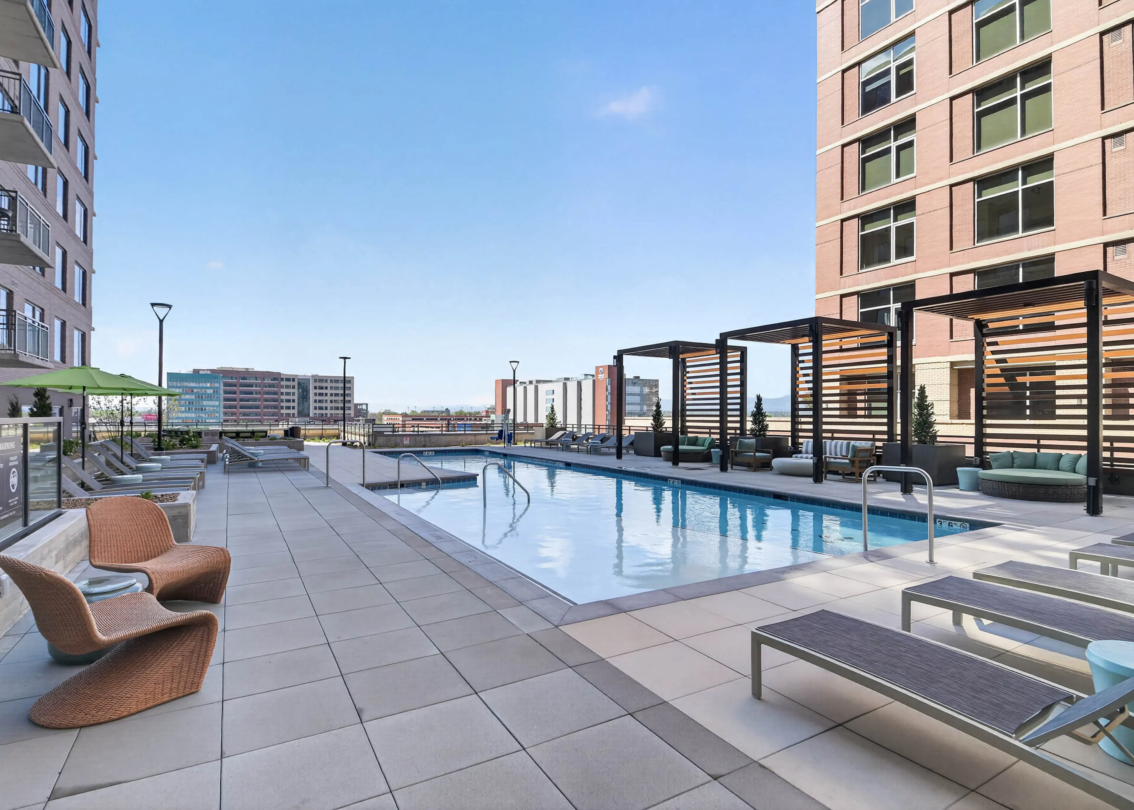 Resident pool at AMLI Golden Triangle apartments with lap pool lounge chairs pergola seating and city skyline views