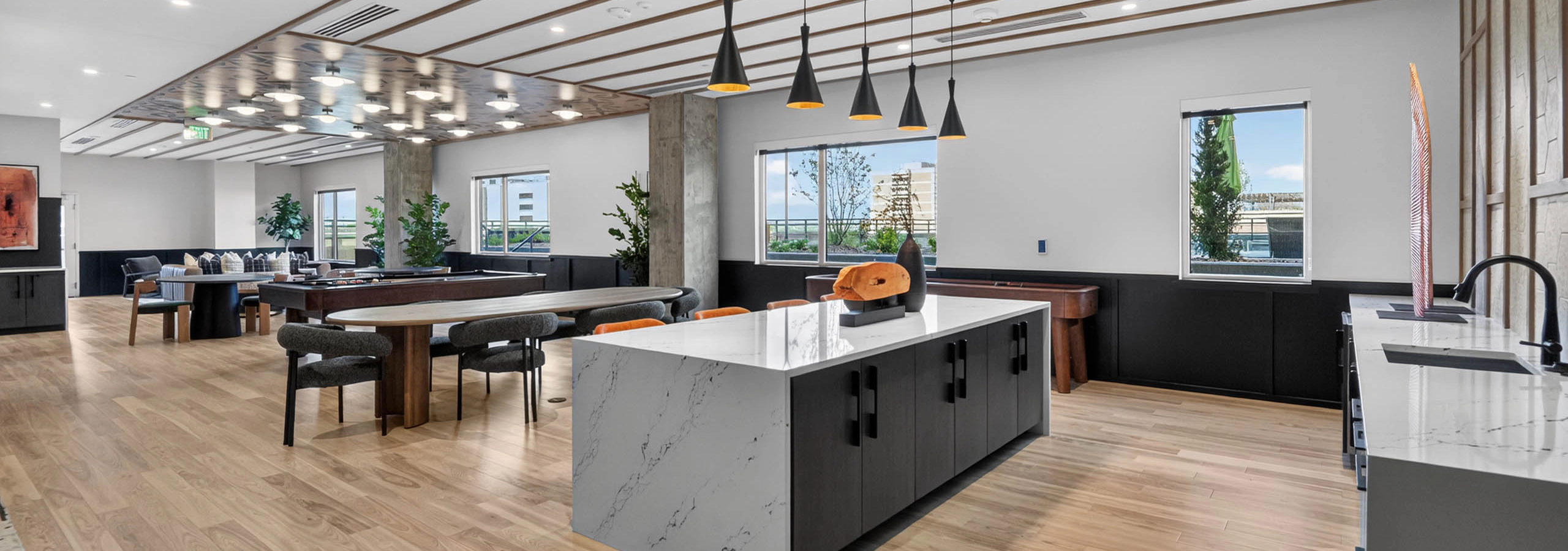 Resident lounge at AMLI Golden Triangle apartments with large island pendant lighting prep space and seating