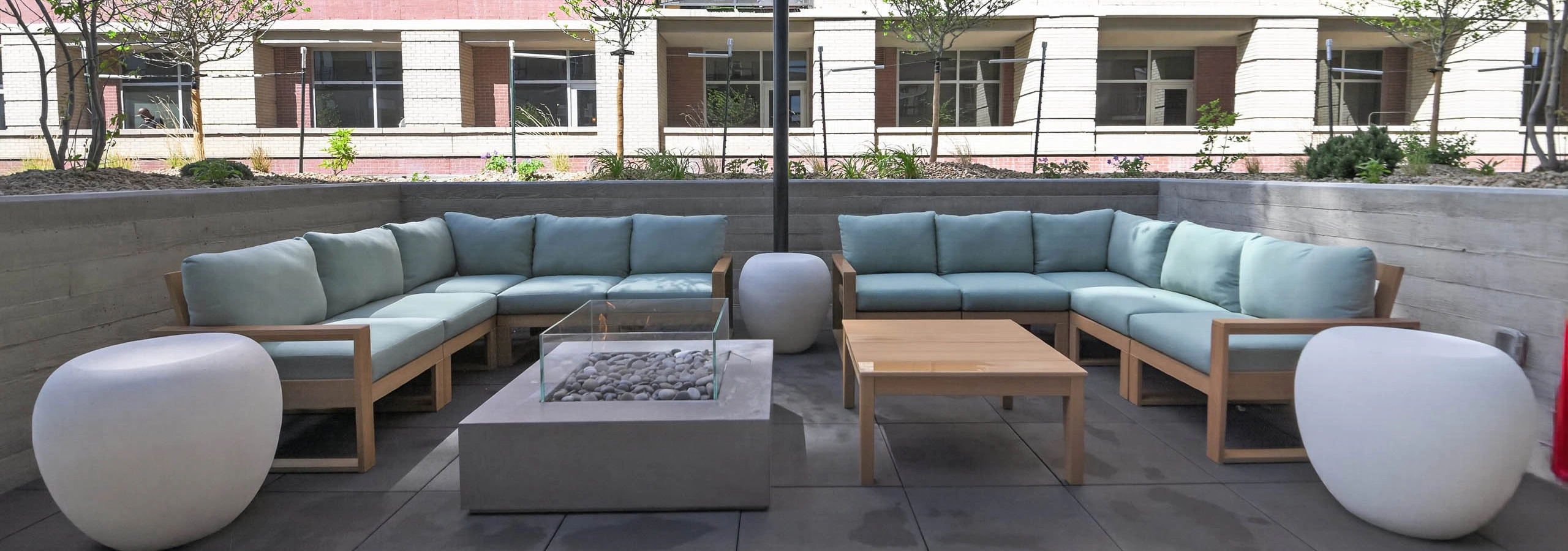 Outdoor lounge at AMLI Golden Triangle apartments with sectional seating fire pit string lights and landscaped courtyard