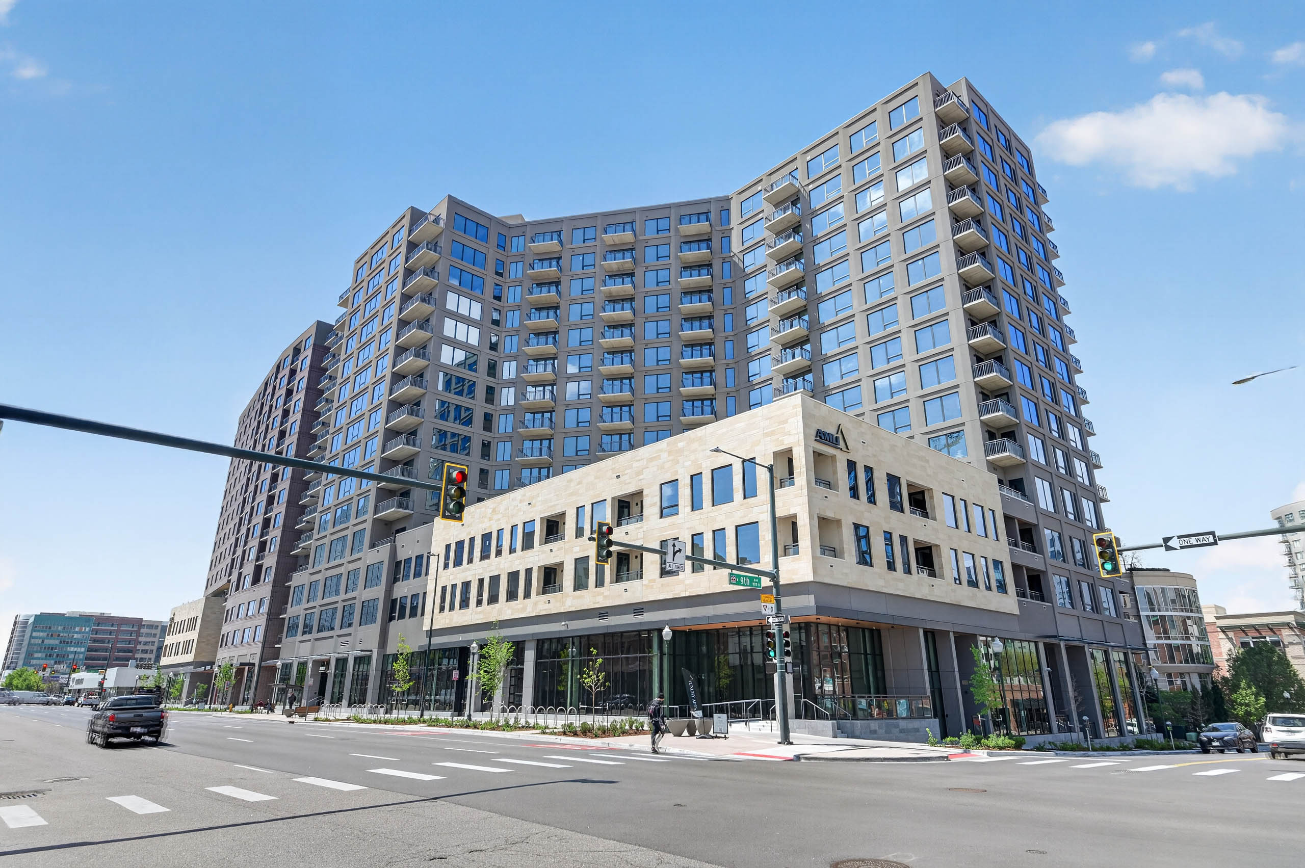 Street level corner view of AMLI Golden Triangle apartment building with modern facade balconies traffic lights and blue sky