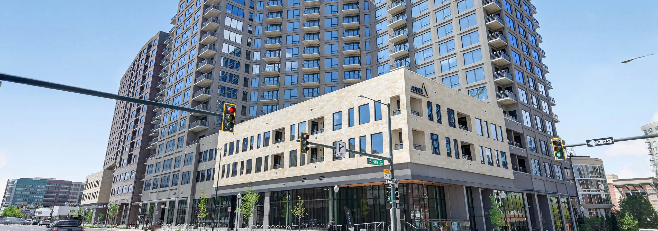 Street level corner view of AMLI Golden Triangle apartment building with modern facade balconies traffic lights and blue sky