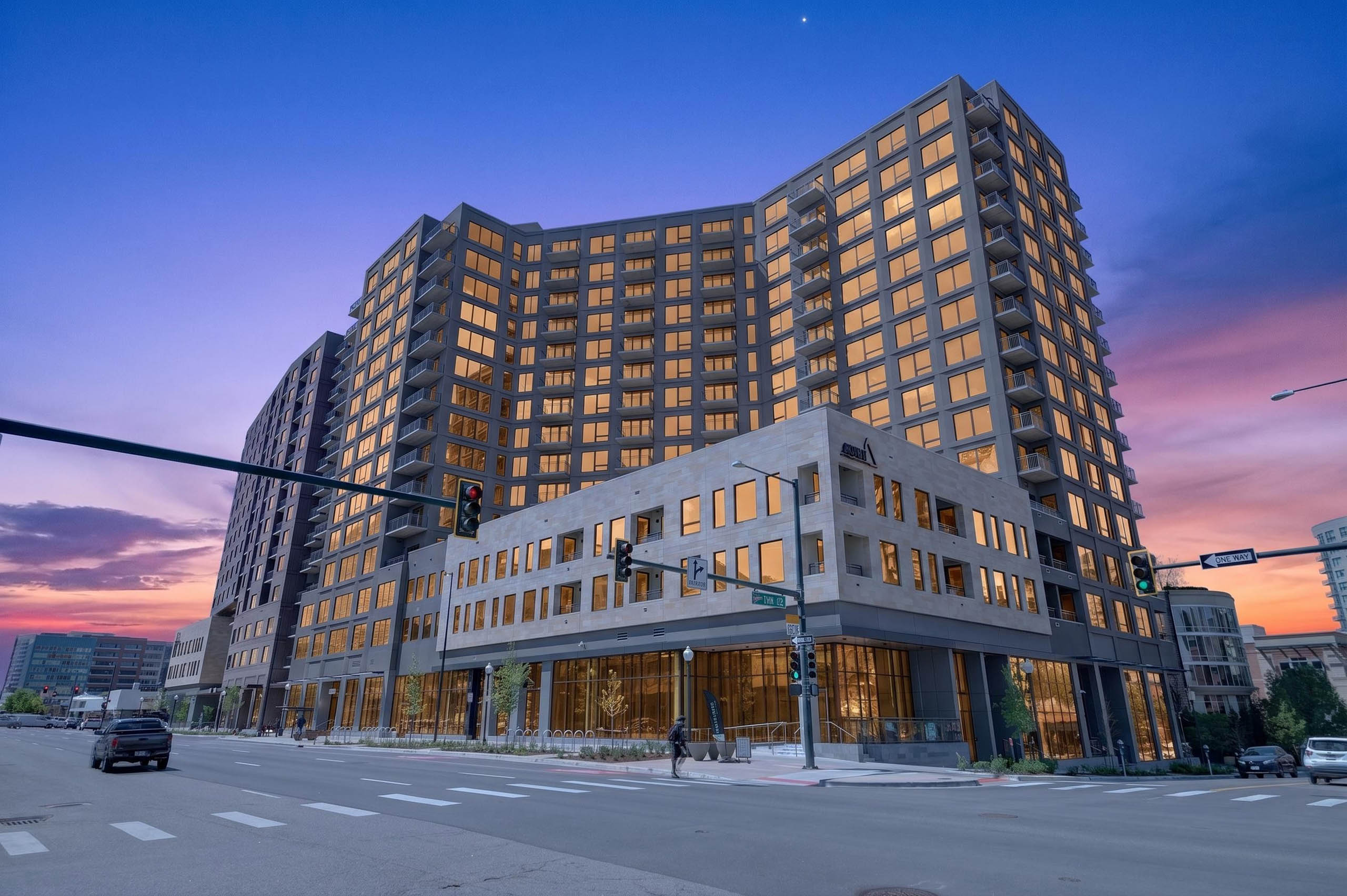 Twilight exterior of AMLI Golden Triangle apartment building with illuminated windows corner intersection and evening sky