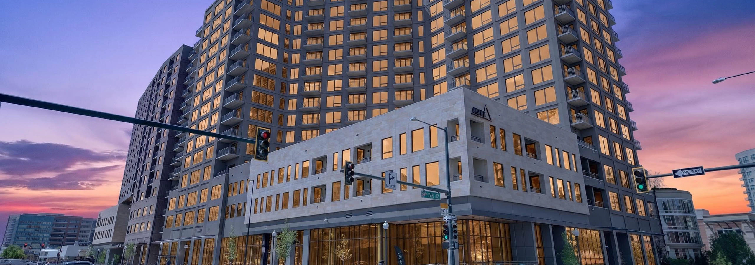 Twilight exterior of AMLI Golden Triangle apartment building with illuminated windows corner intersection and evening sky