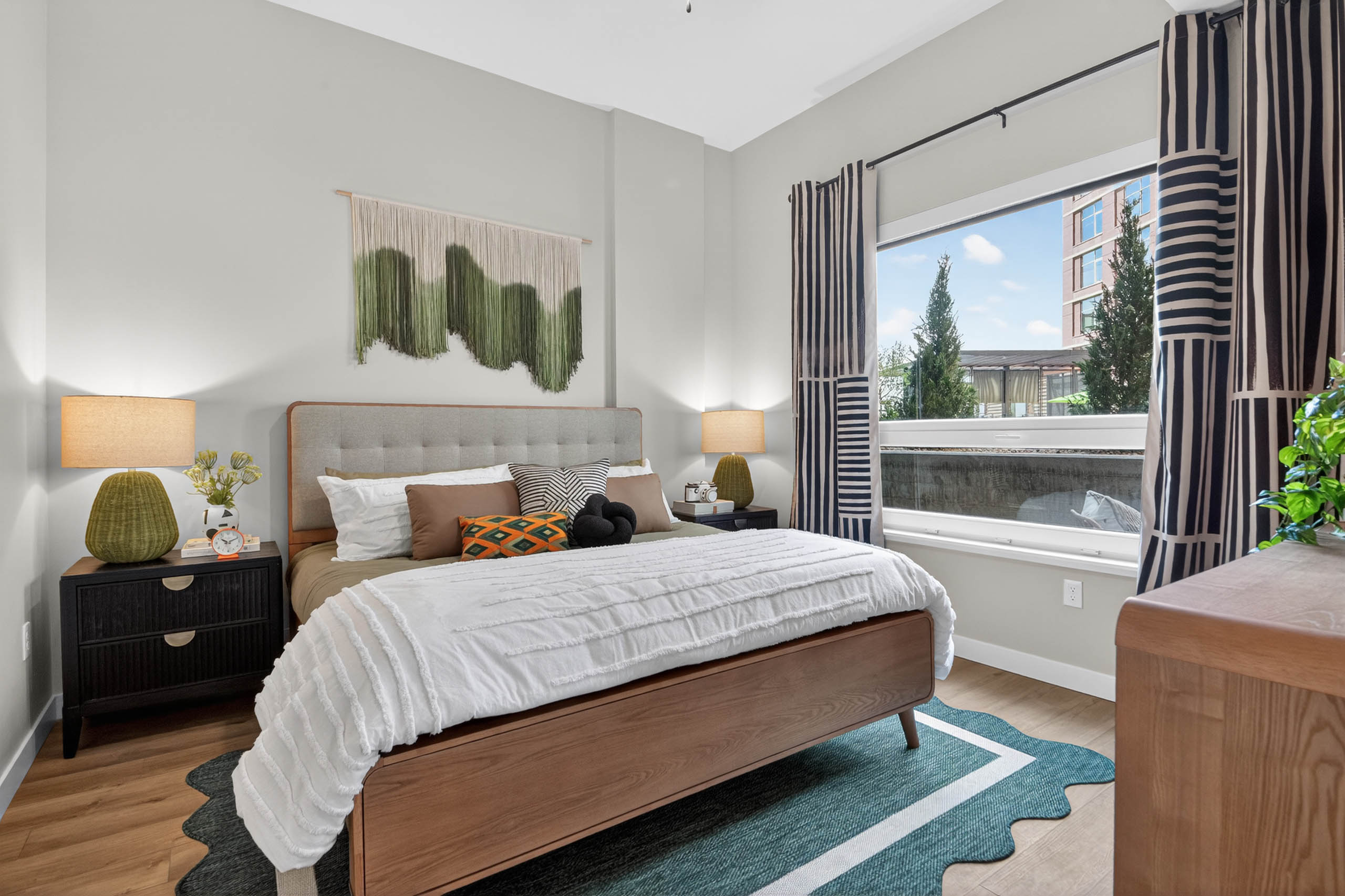 Bedroom at AMLI Golden Triangle apartment with upholstered bed nightstands framed art window and natural light