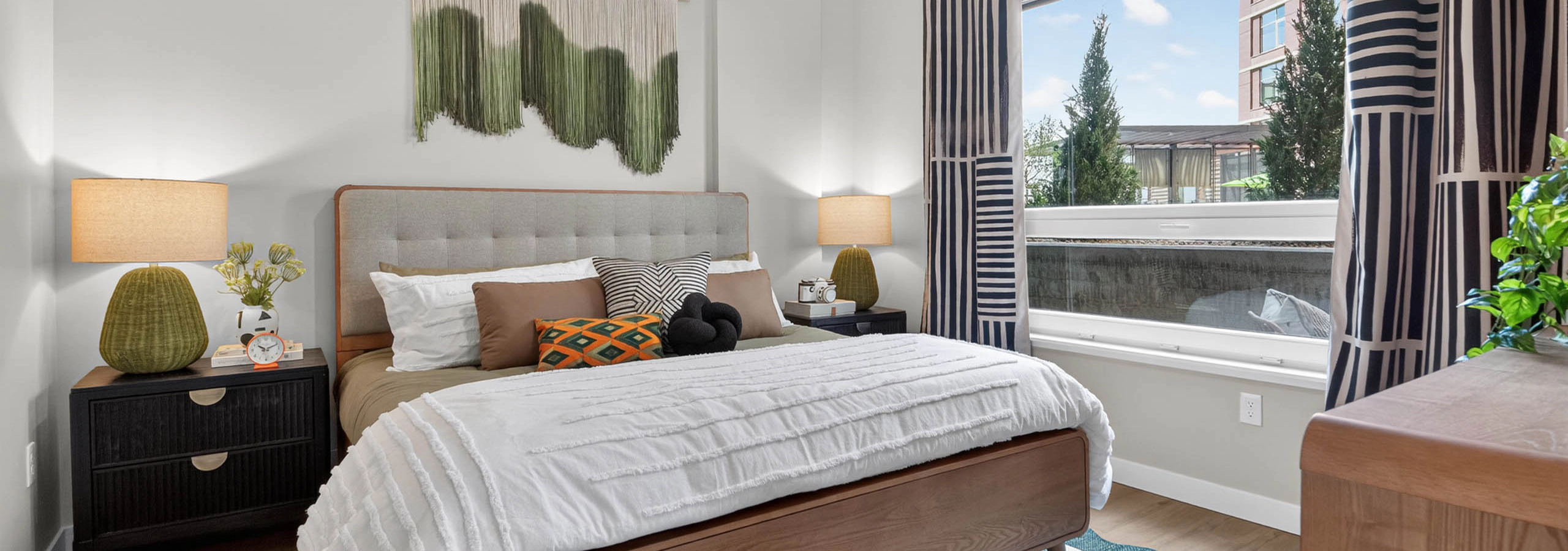 Bedroom at AMLI Golden Triangle apartment with upholstered bed nightstands framed art window and natural light