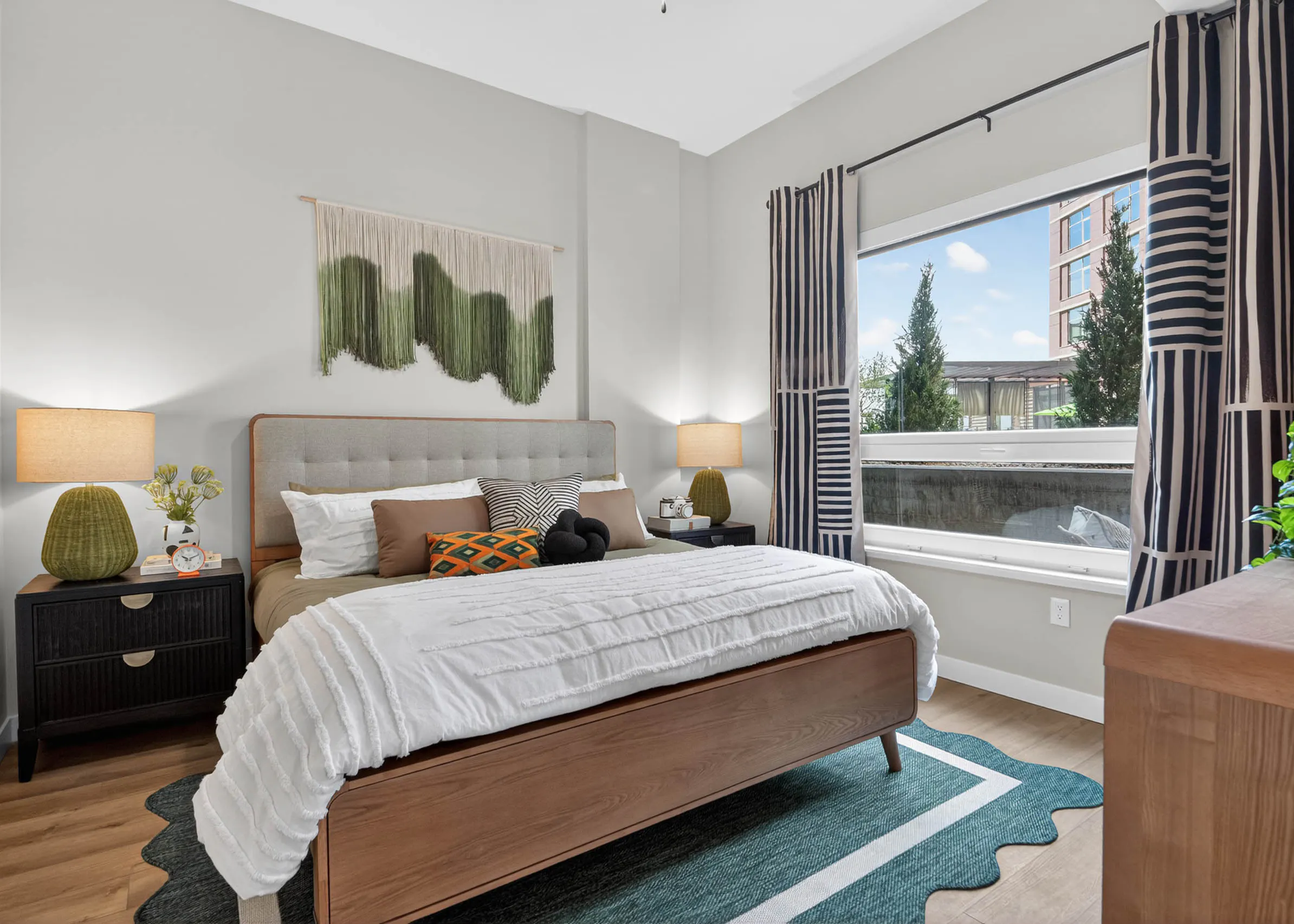 Bedroom at AMLI Golden Triangle apartment with upholstered bed nightstands framed art window and natural light