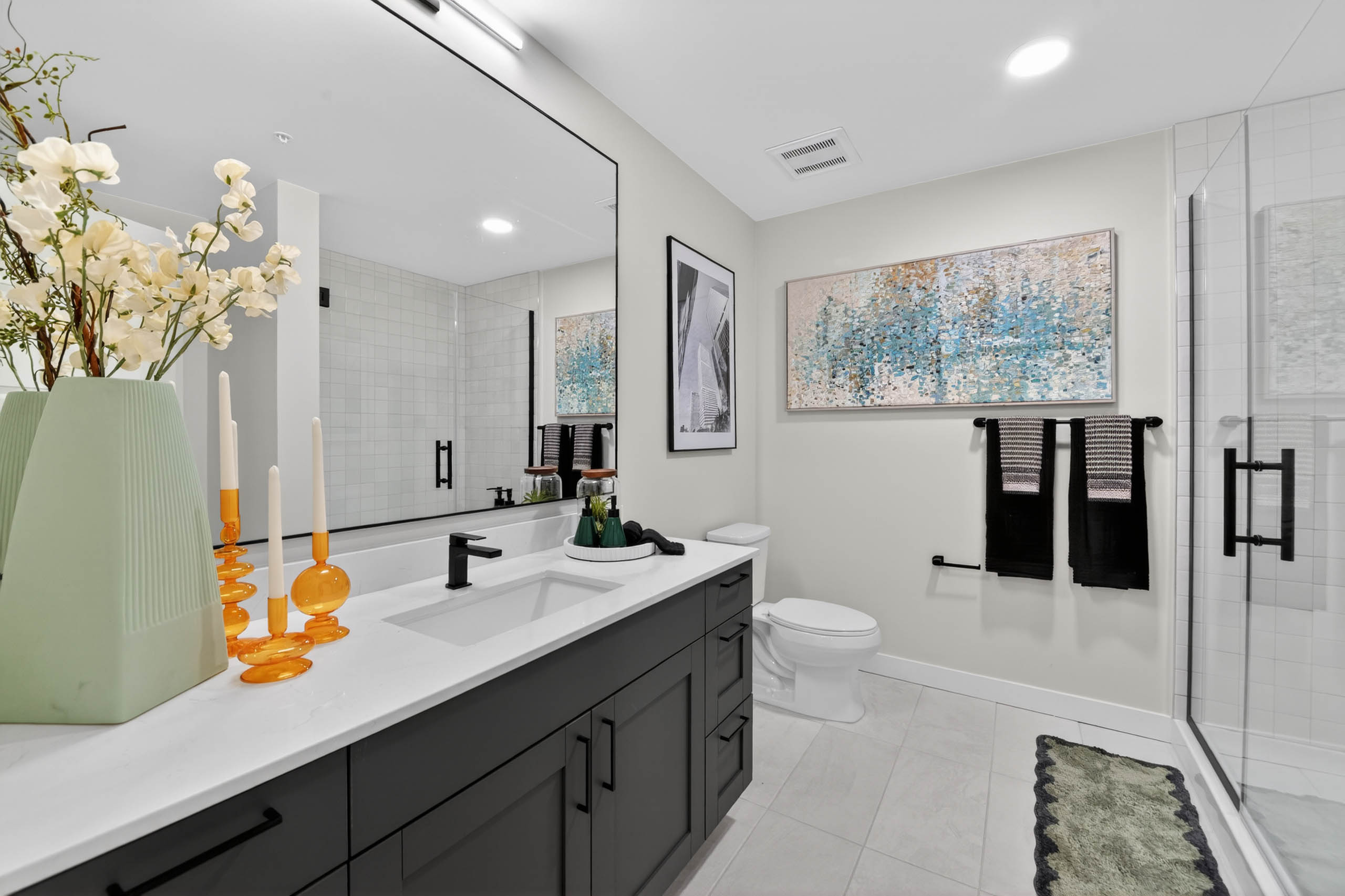 Bathroom at AMLI Golden Triangle apartment with double sink vanity large mirror glass shower and modern finishes