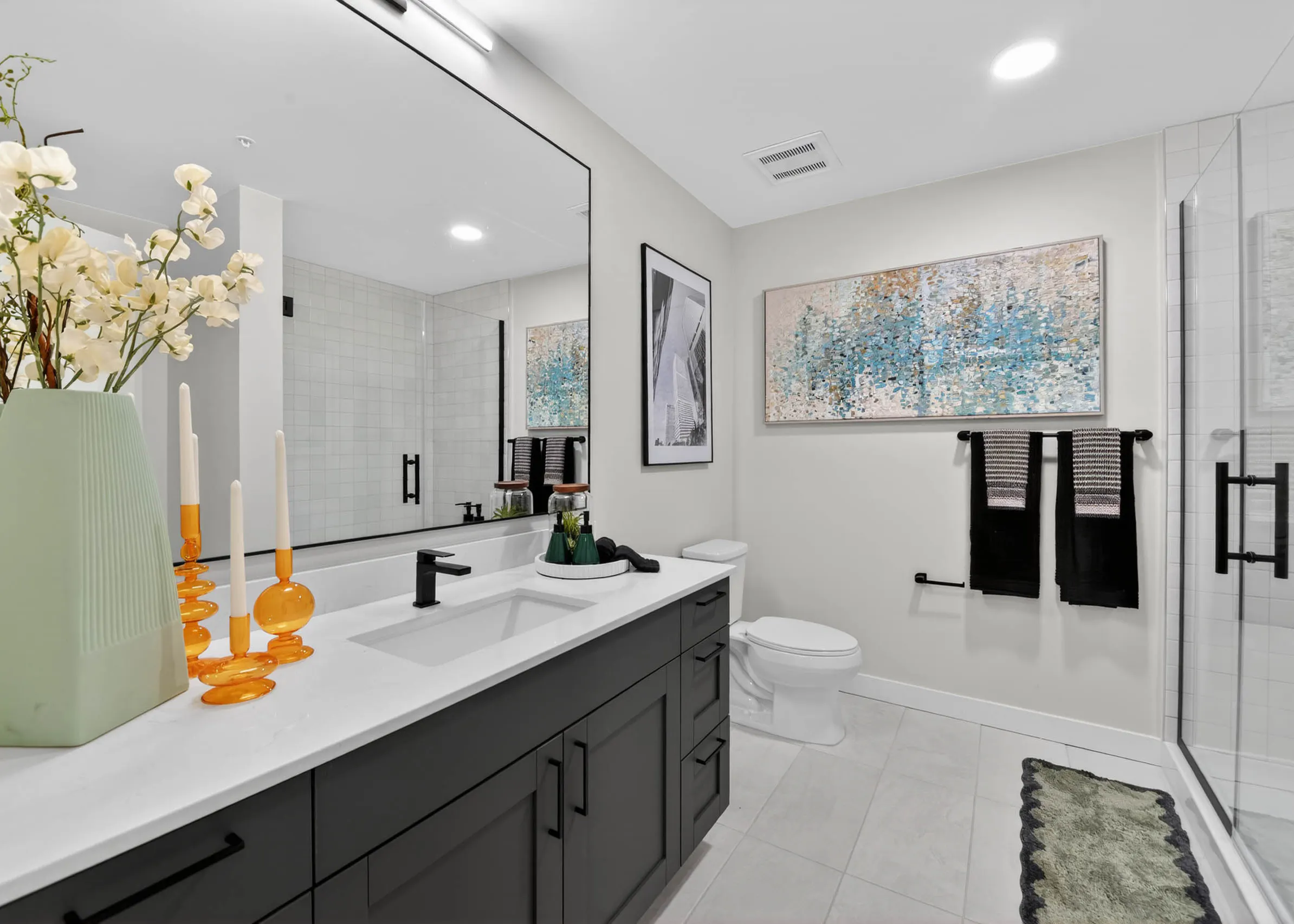Bathroom at AMLI Golden Triangle apartment with double sink vanity large mirror glass shower and modern finishes